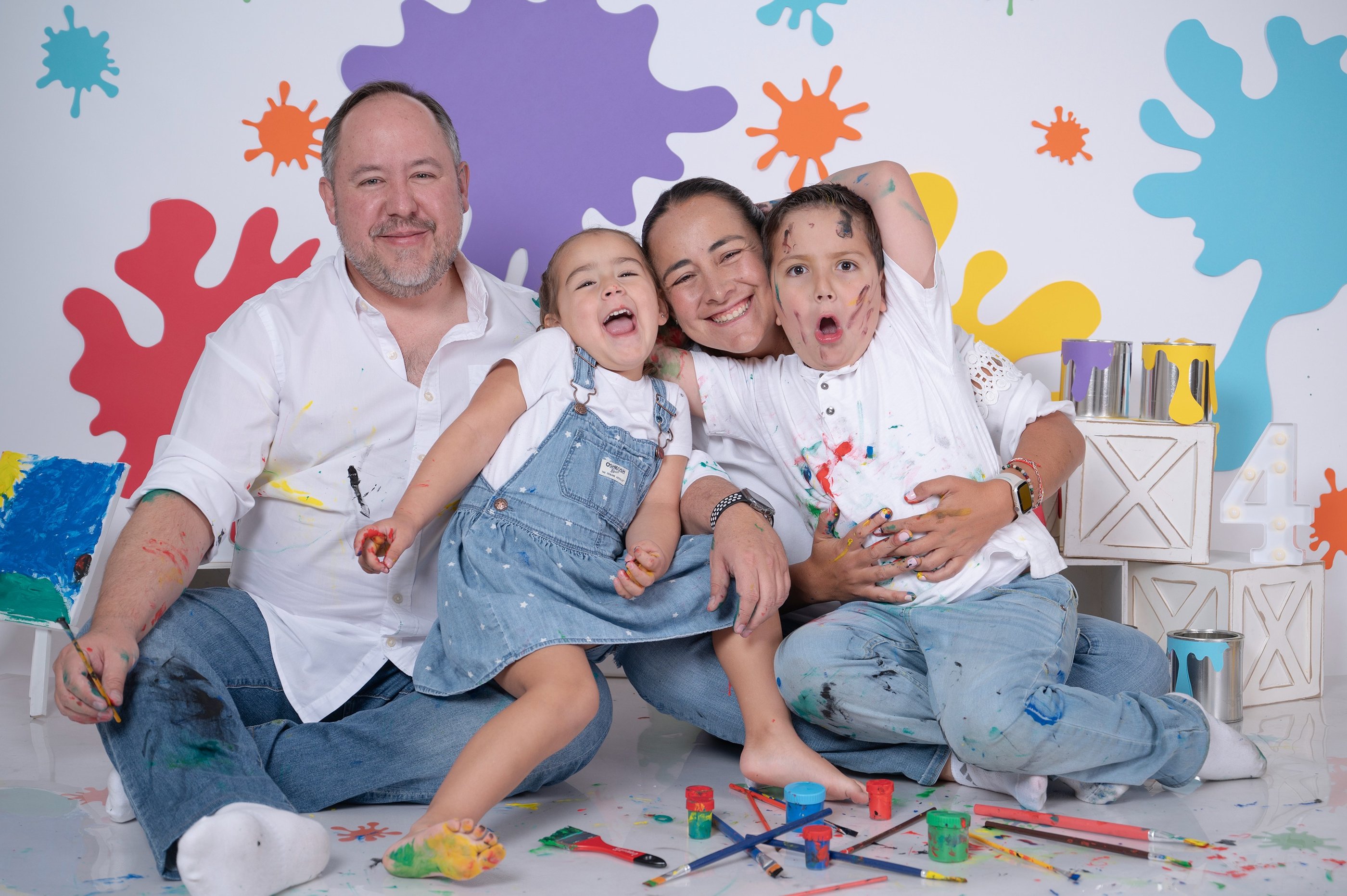 a family posing for a photo in front of a wall with paint splatters