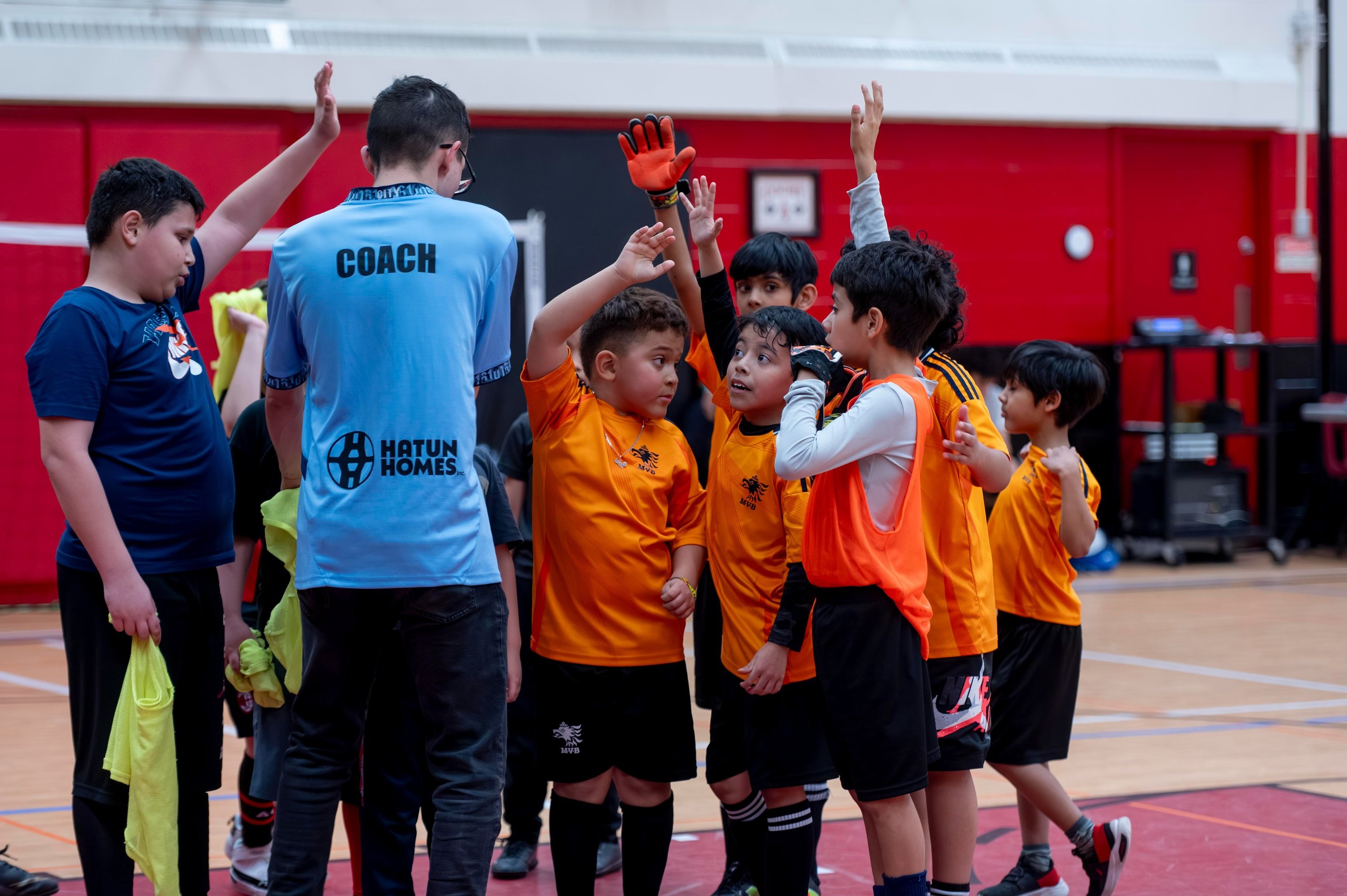 MVB FC soccer players  and their coach high-fiving during an indoor futsal game. Mississauga Soccer 