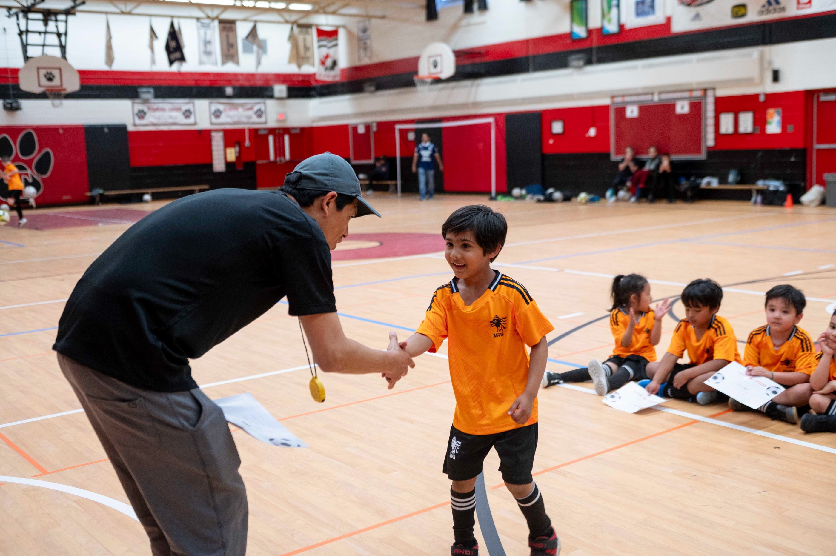 A youth indoor soccer coach shakes hands with a young player at MVB FC during Soccer class.