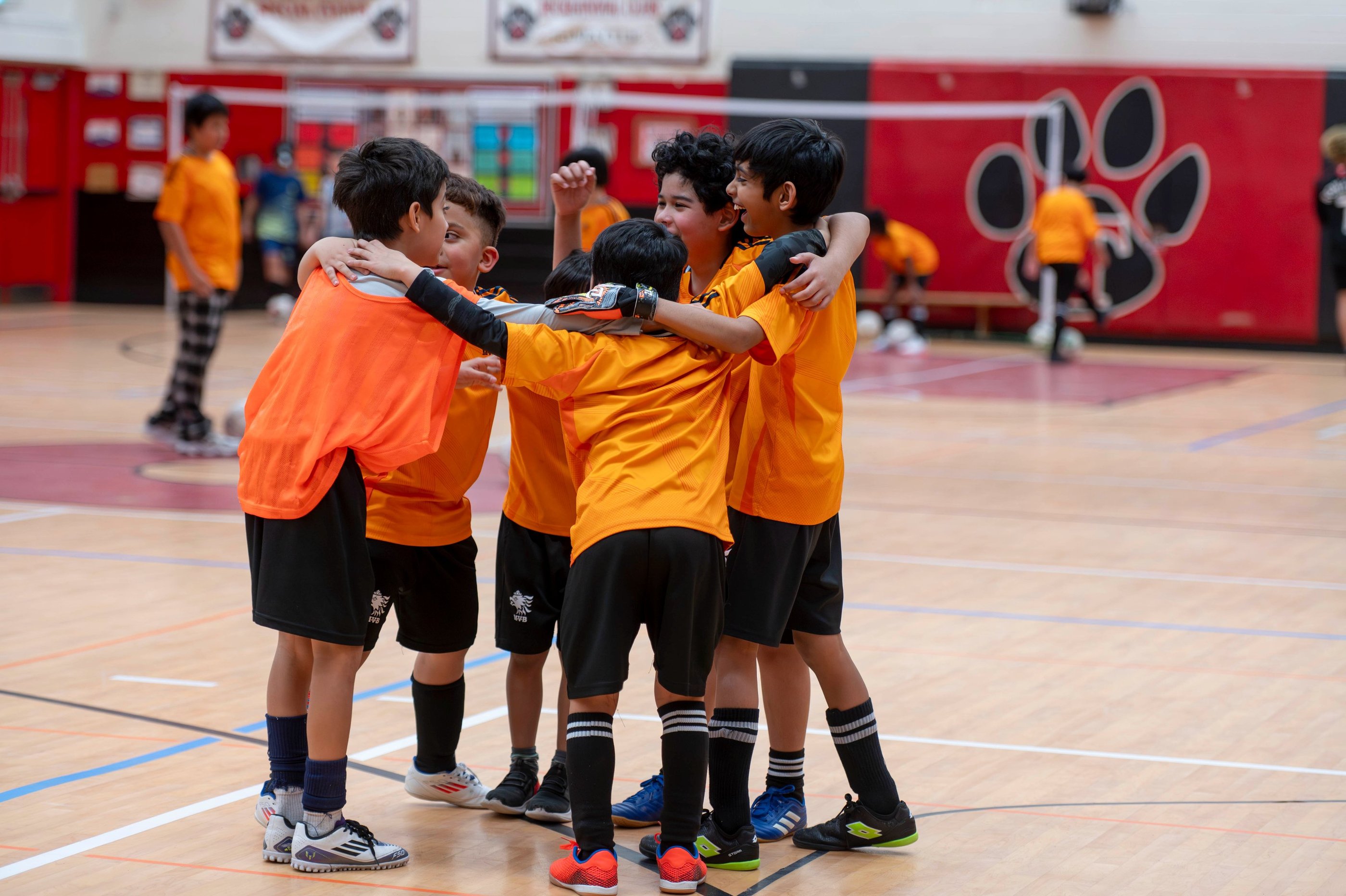 Young boys in MVB FC jerseys celebrating during an indoor soccer match in Soccer School Mississauga