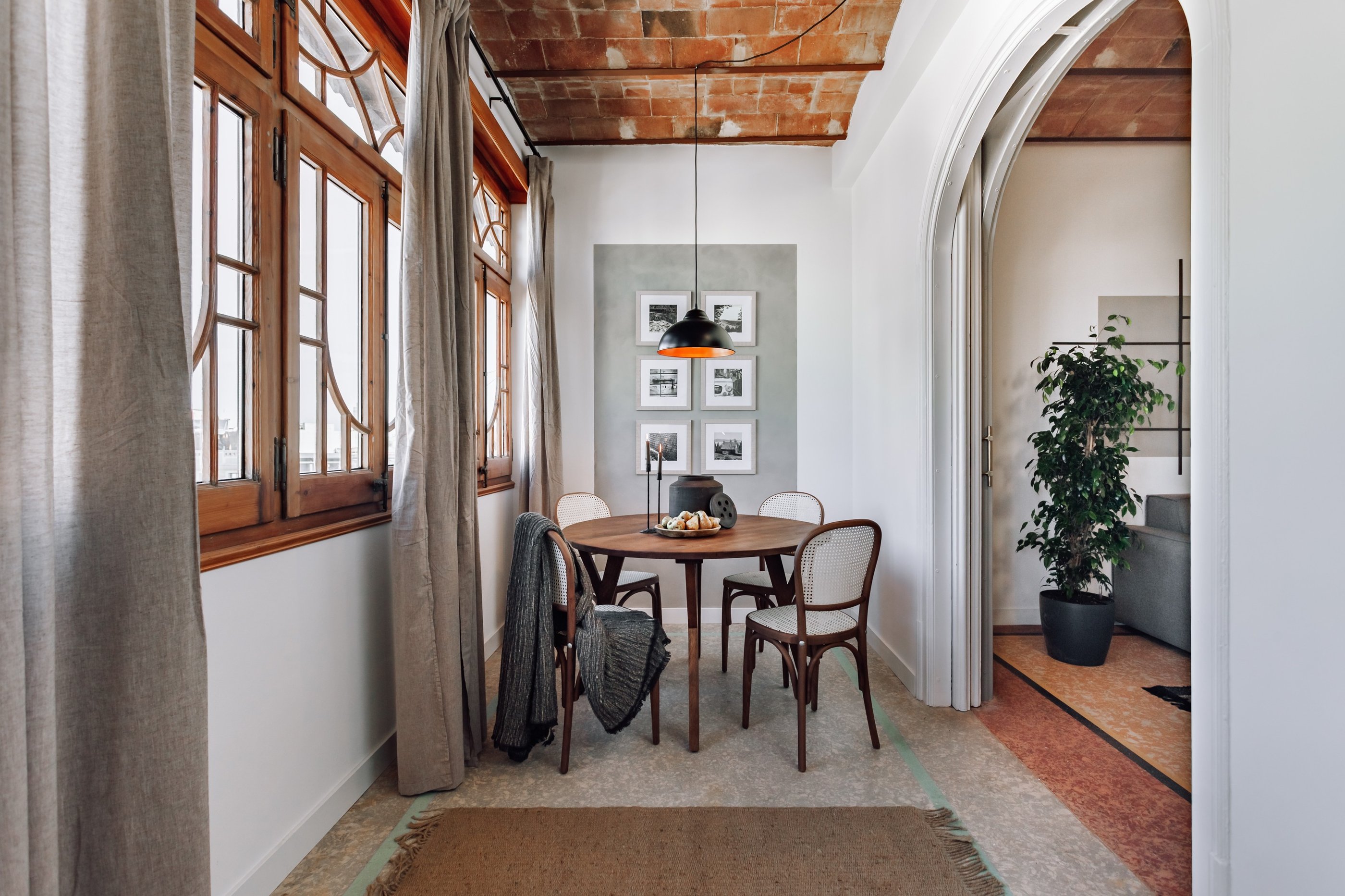 Elegant dining area with rattan and wood chairs and rustic decor elements by SAVIA interior design