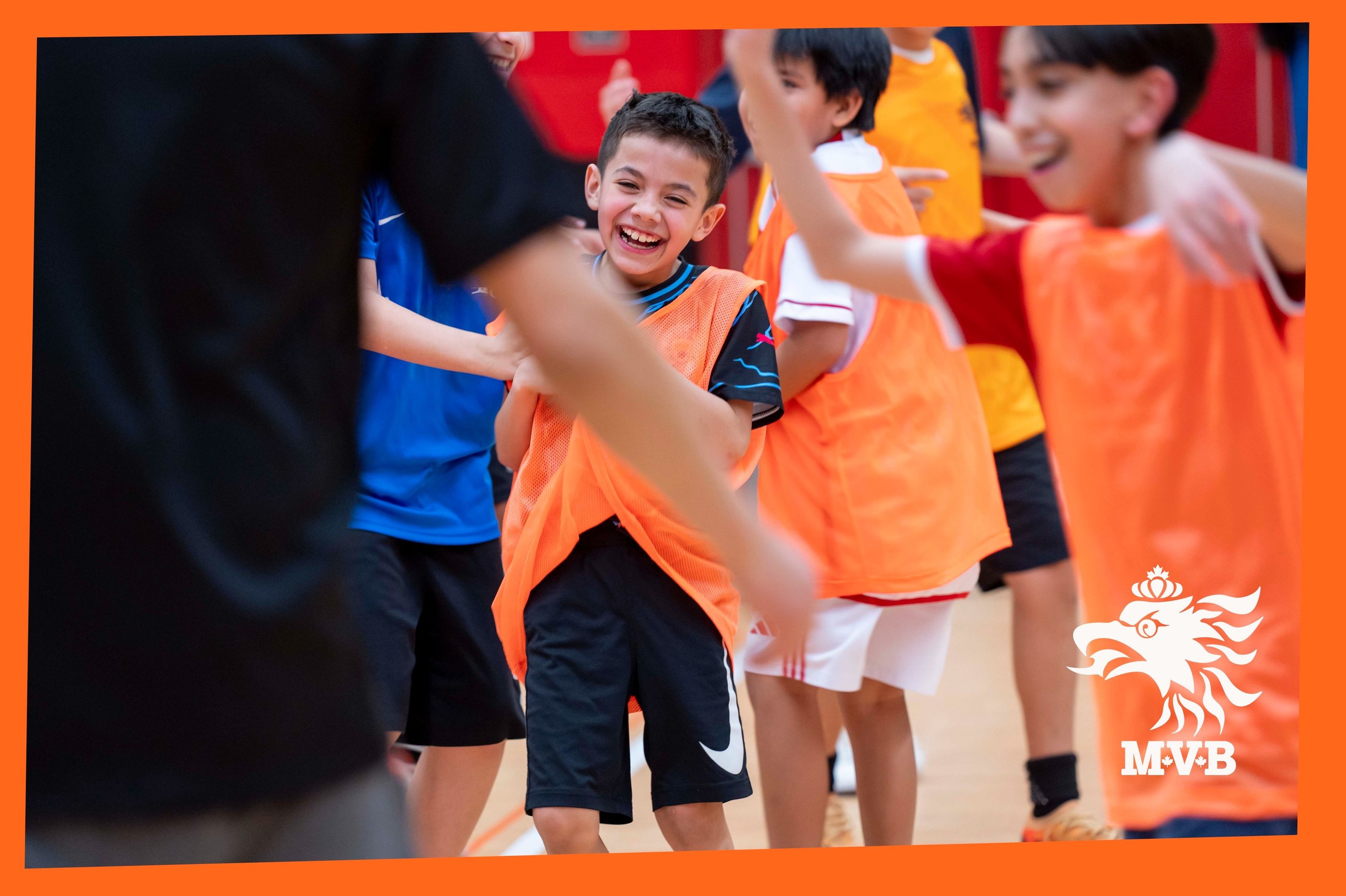 Smiling young MVB FC soccer student playing youth indoor soccer with teammates in Mississauga