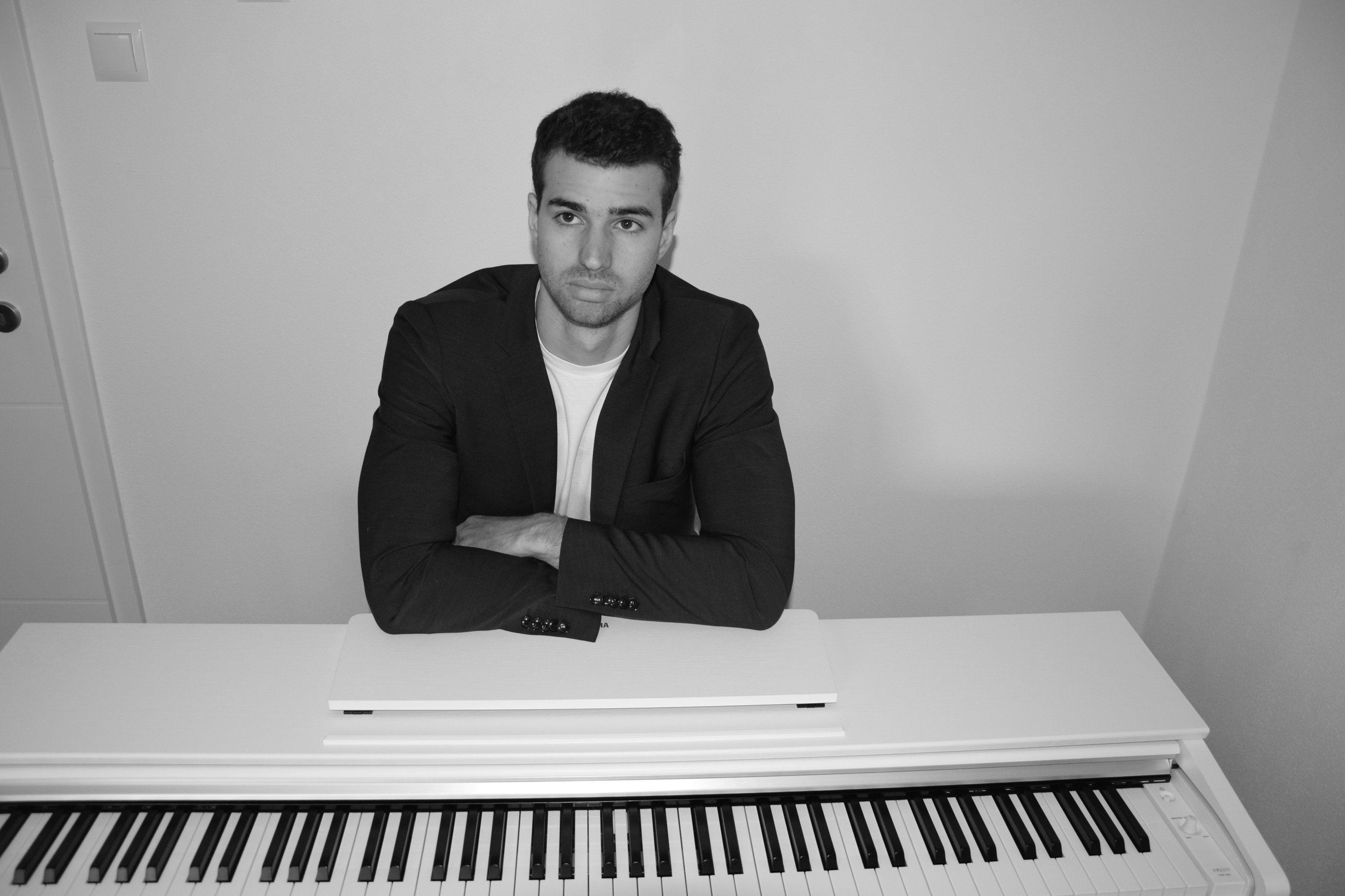 a man in a suit and tie sitting at a piano