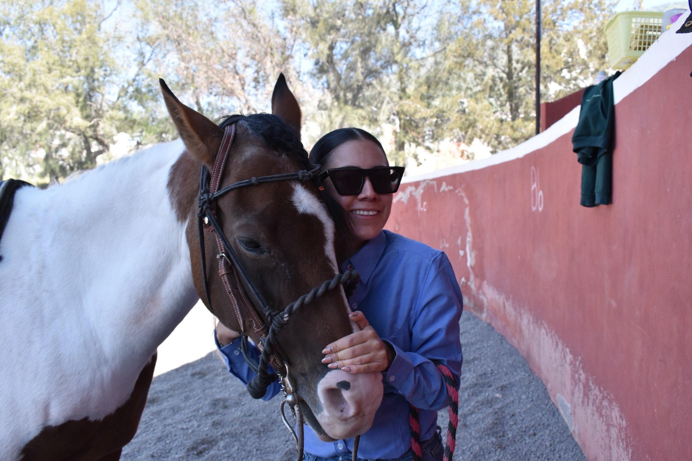 a woman in sunglasses and sunglasses is holding a horse