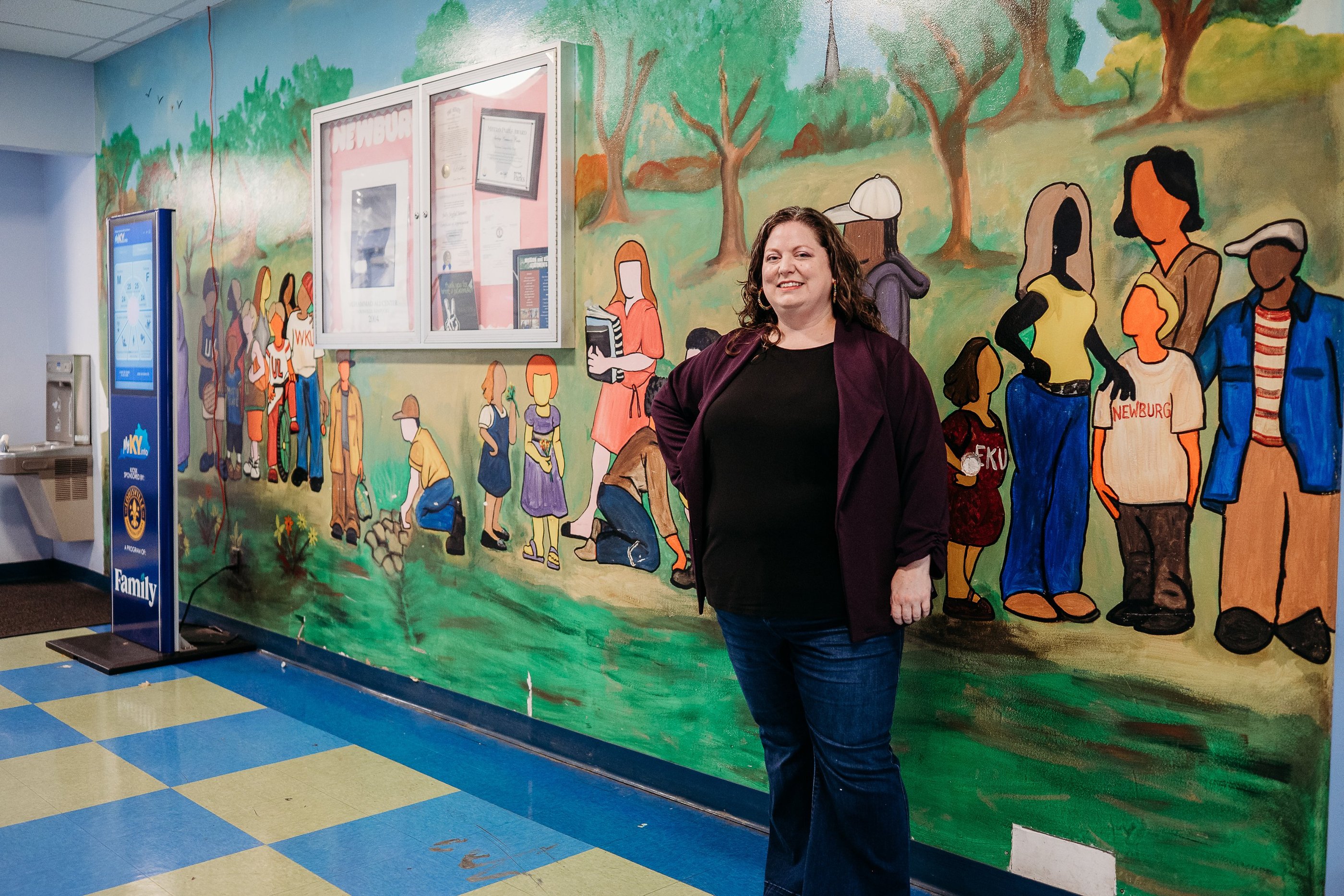 Woman in purple sweater standing in front of painted mural