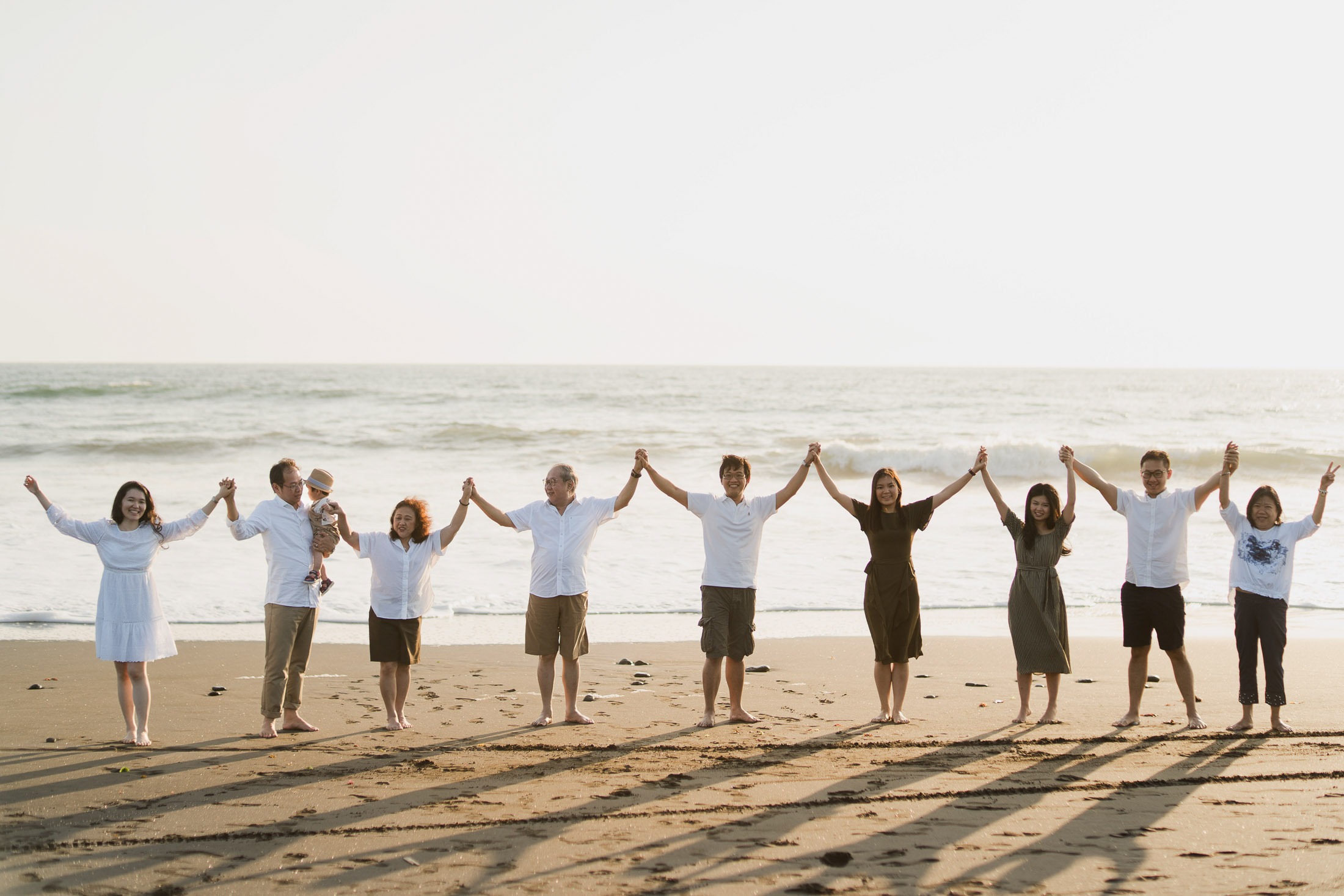 Large multi generation family standing together on Nyanyi Beach in Tabanan Bali during a sunset family photography session