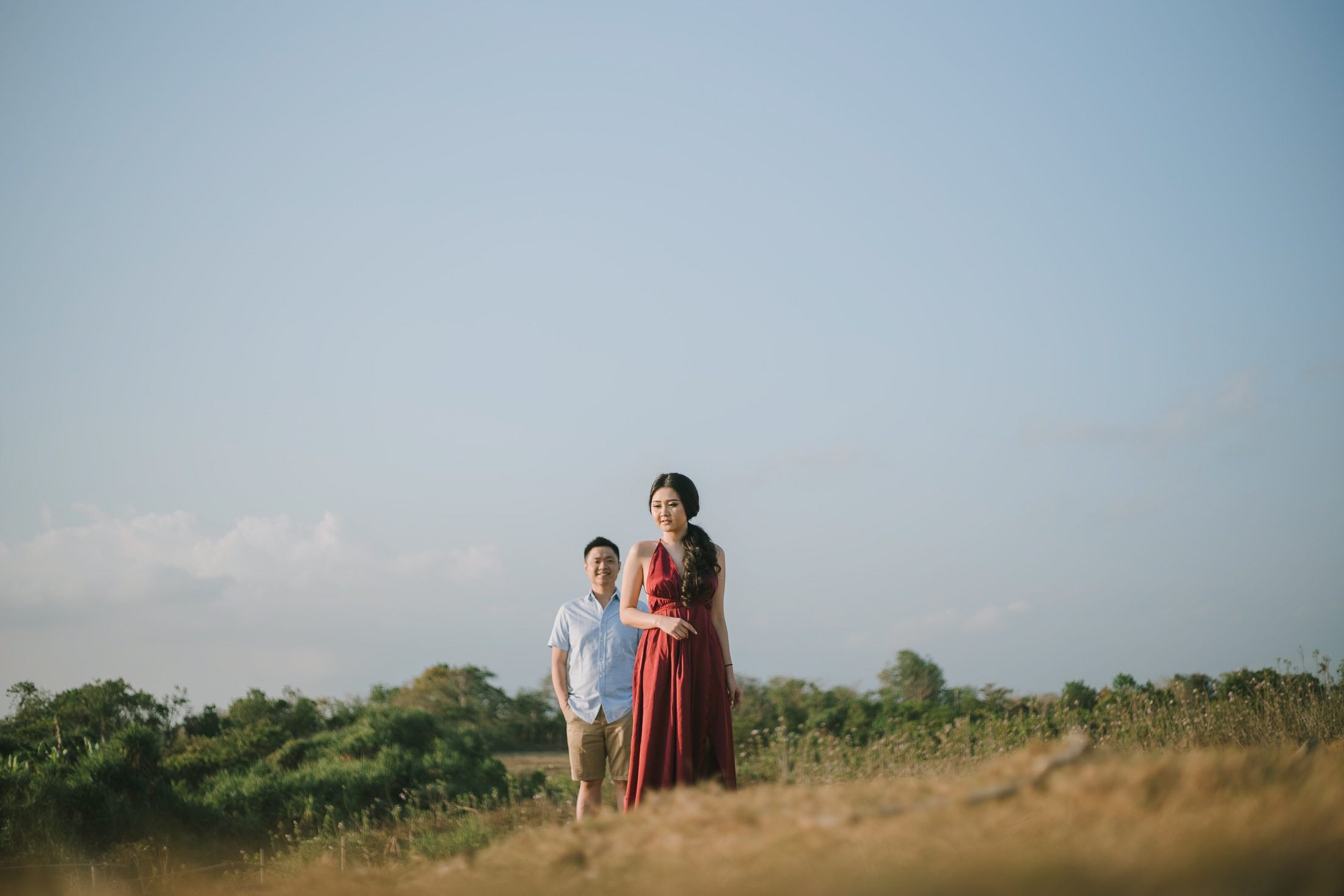 Wide sunset portrait of intimate couple in open field at Pantai Nyanyi Bali.