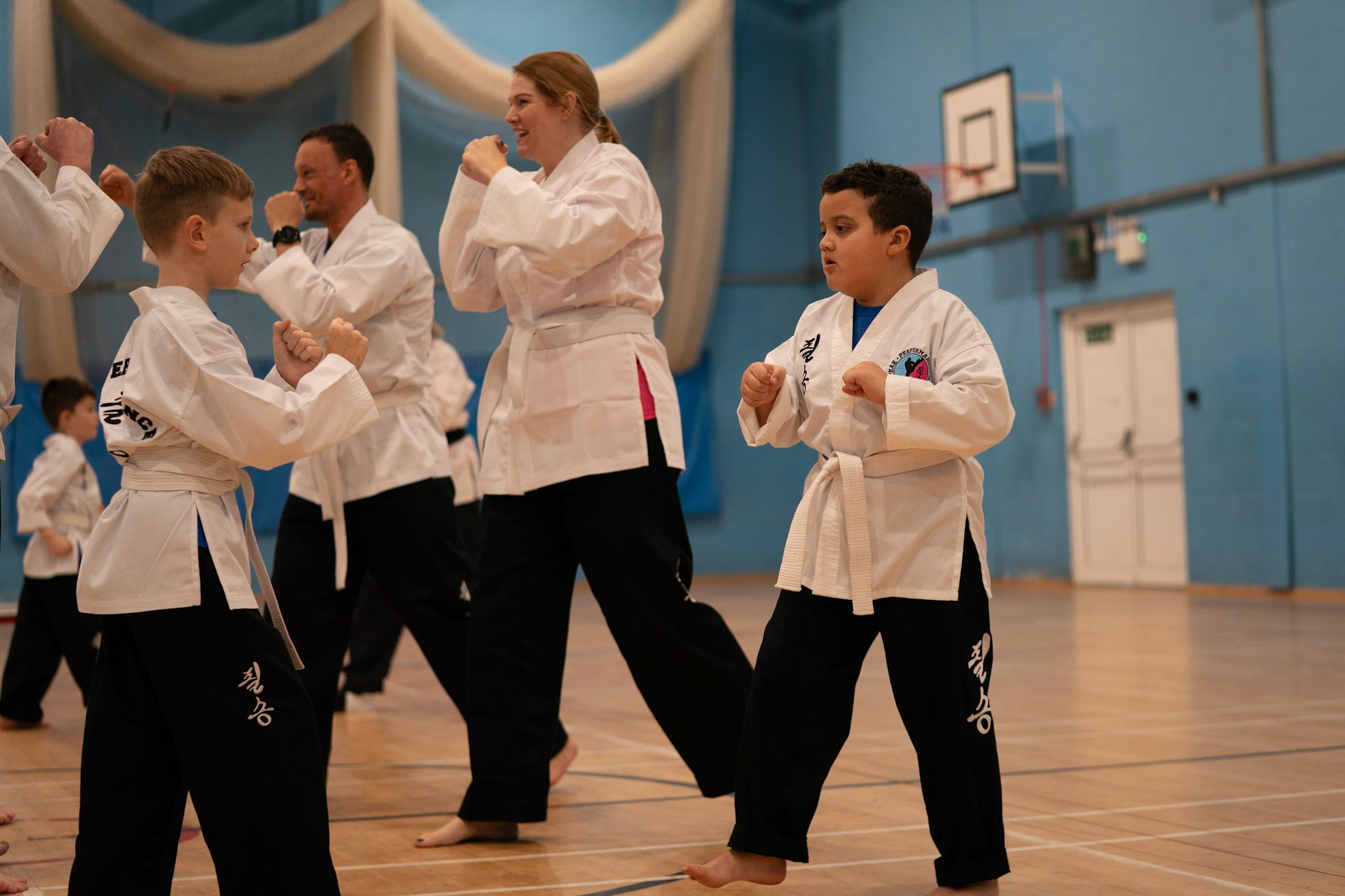 Students in white uniforms practicing martial arts techniques during a Choi Kwang Do class.