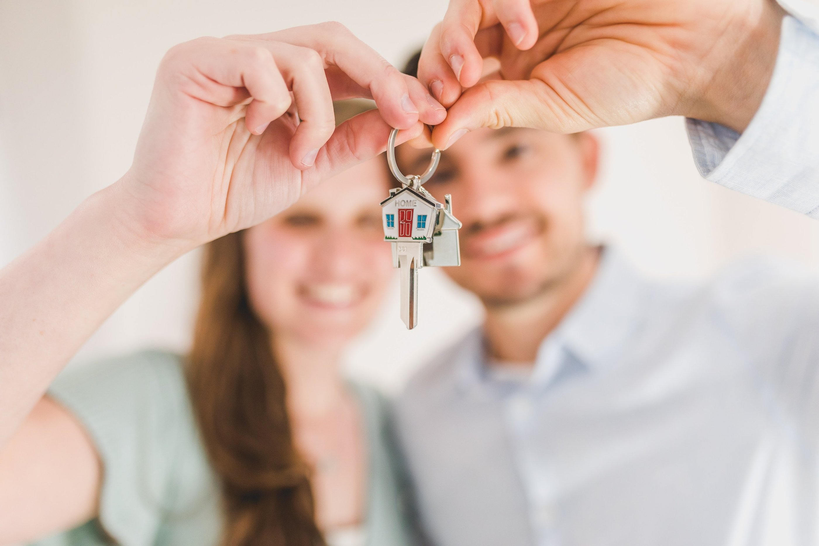 happy couple holding keys to a house after reading the guidebook created your neighbourhood surveyor