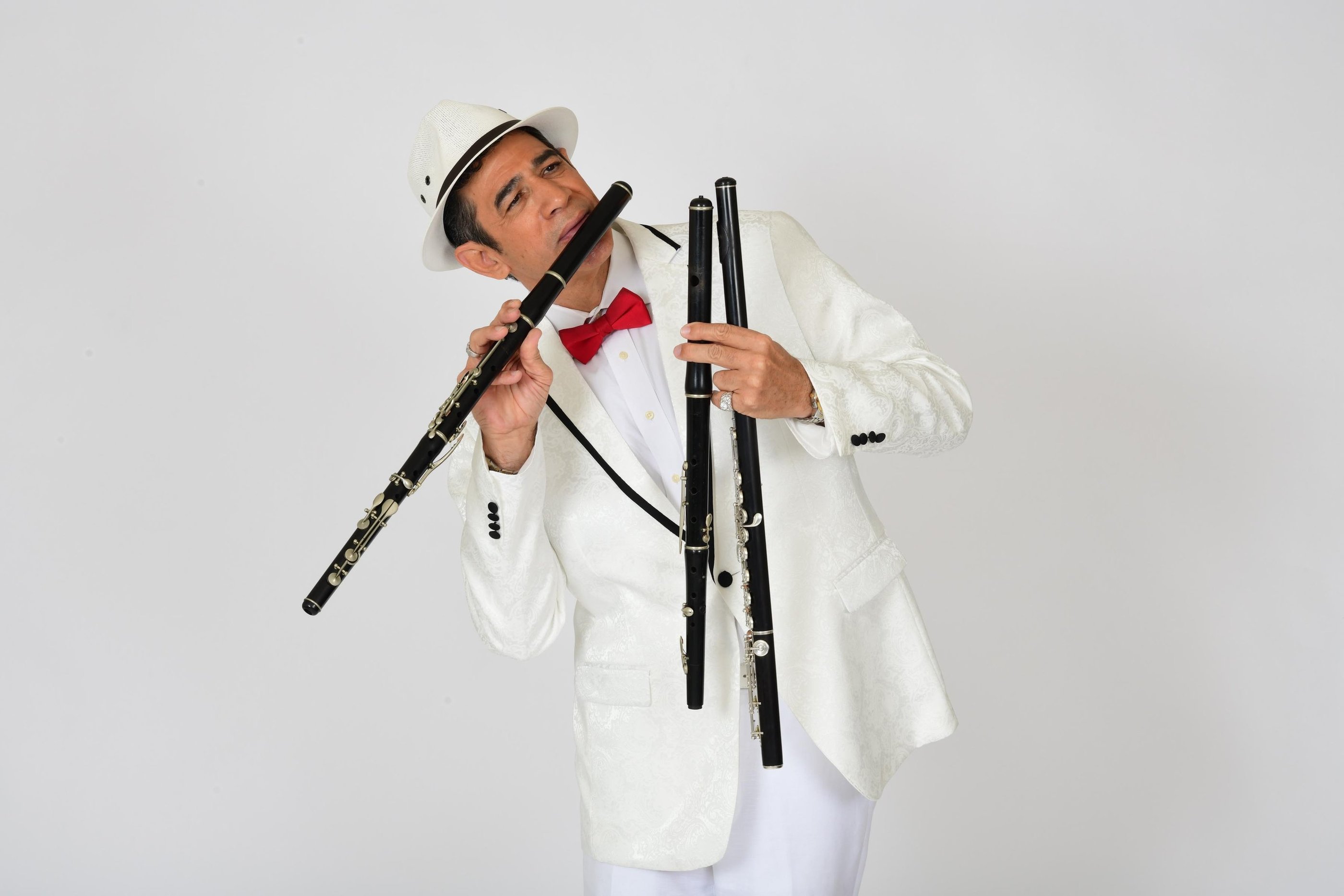 Maestro Bobby Ramirez in white suit playing flute