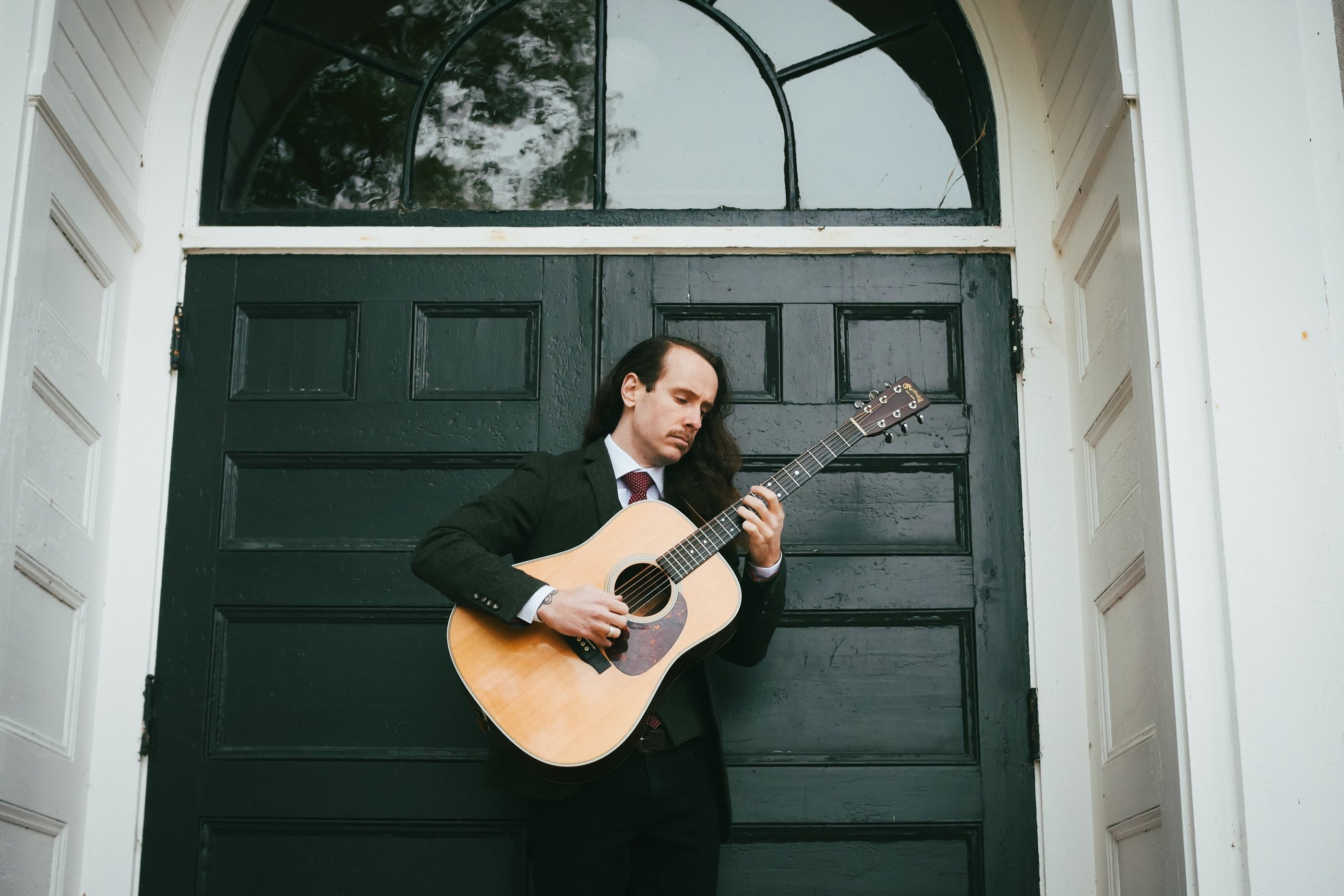 a man in a suit and tie playing guitar
