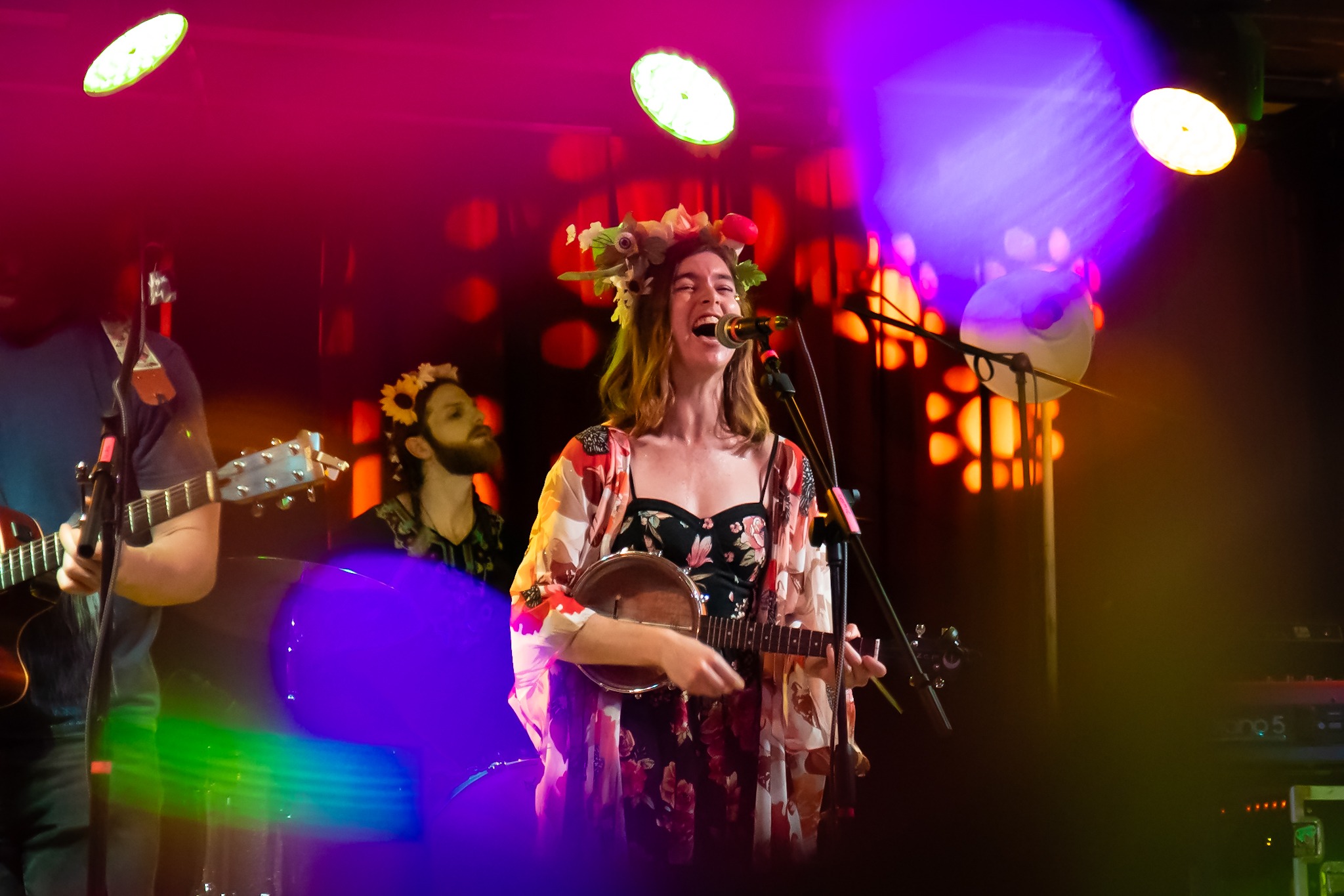 a woman singing and playing guitar in a band