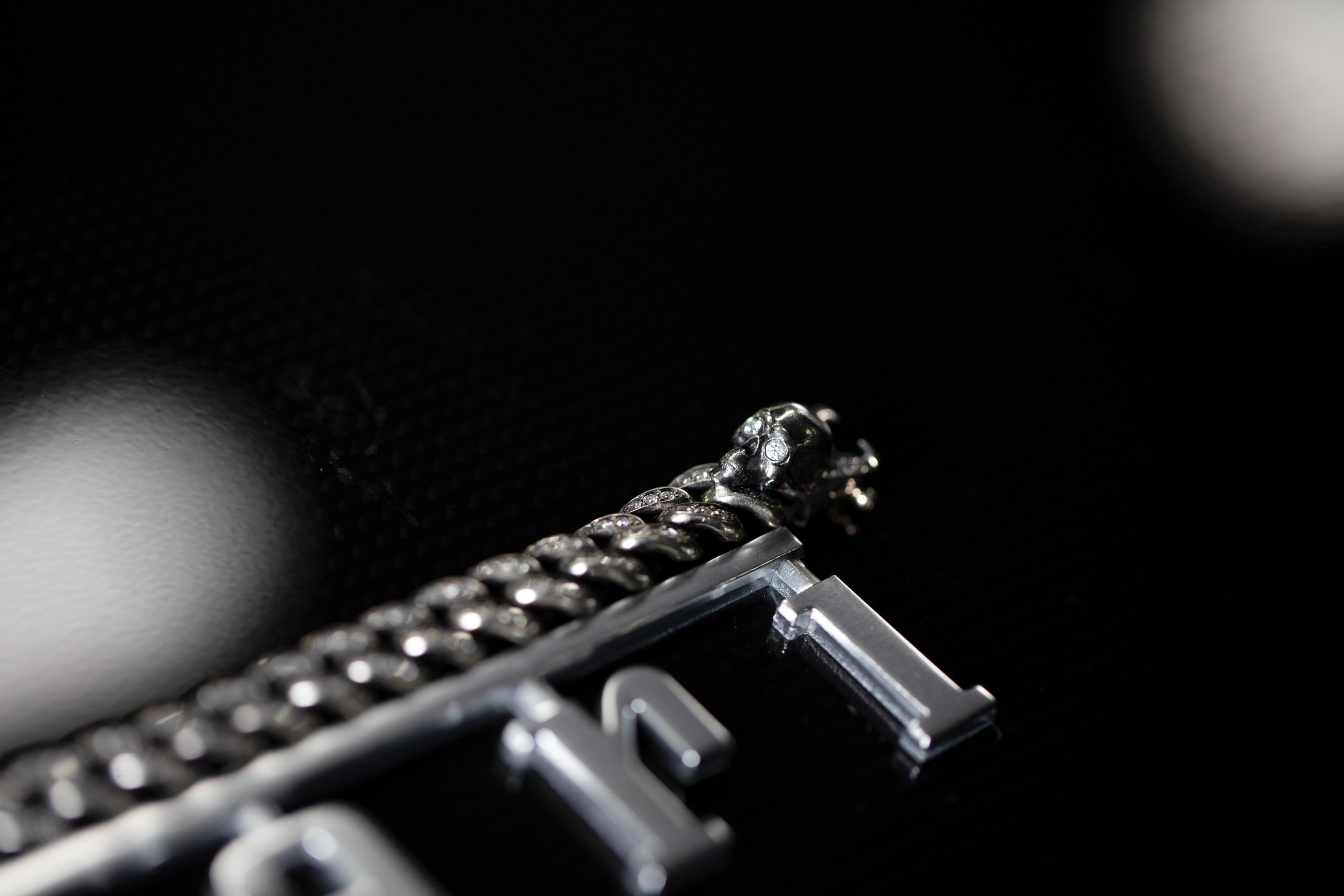 Macro product photo of a silver bracelet and metal pendant on a black background