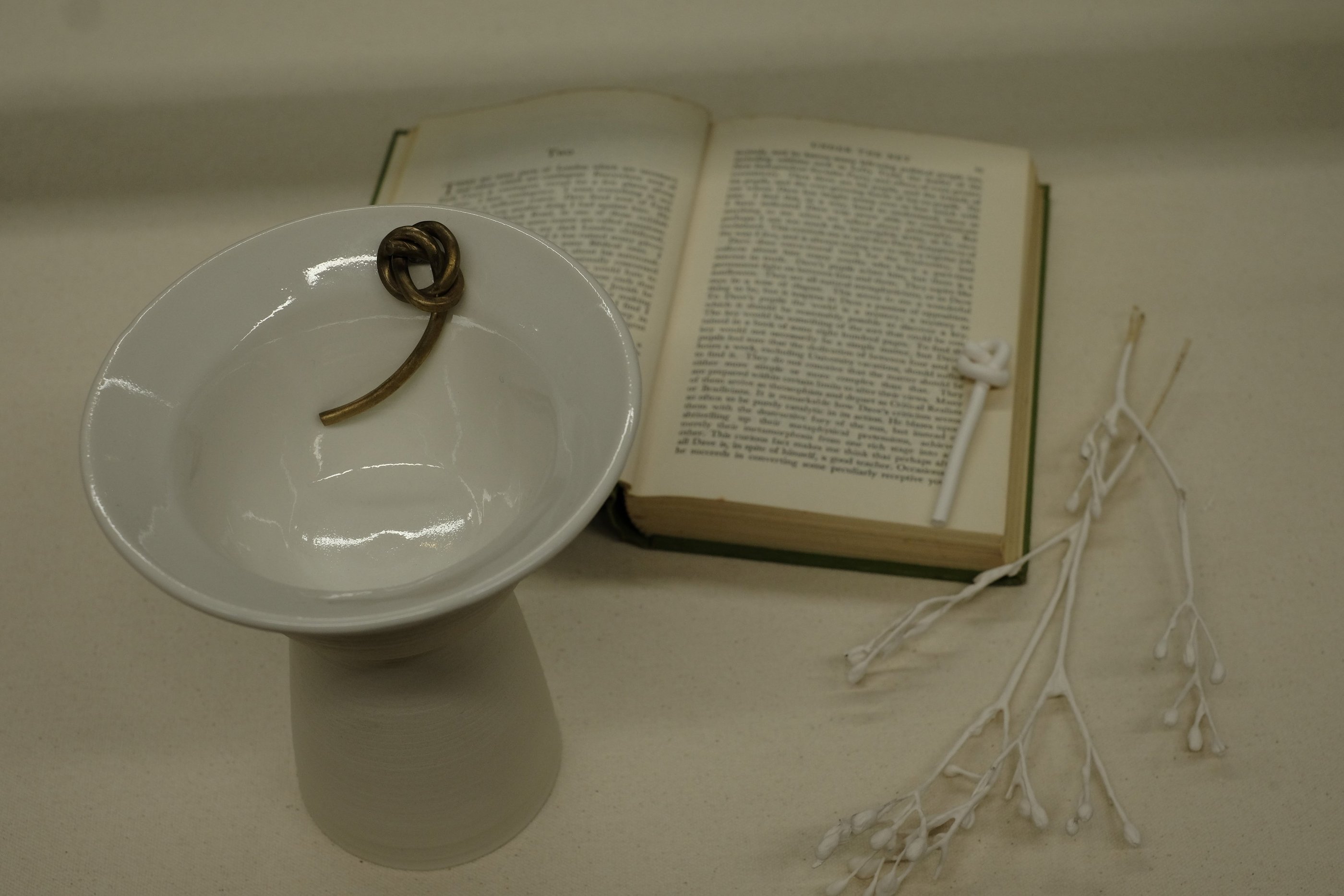 Assemblage including a porcelain vessel with sculptural bronze knot detail and Iris Murdoch novel 