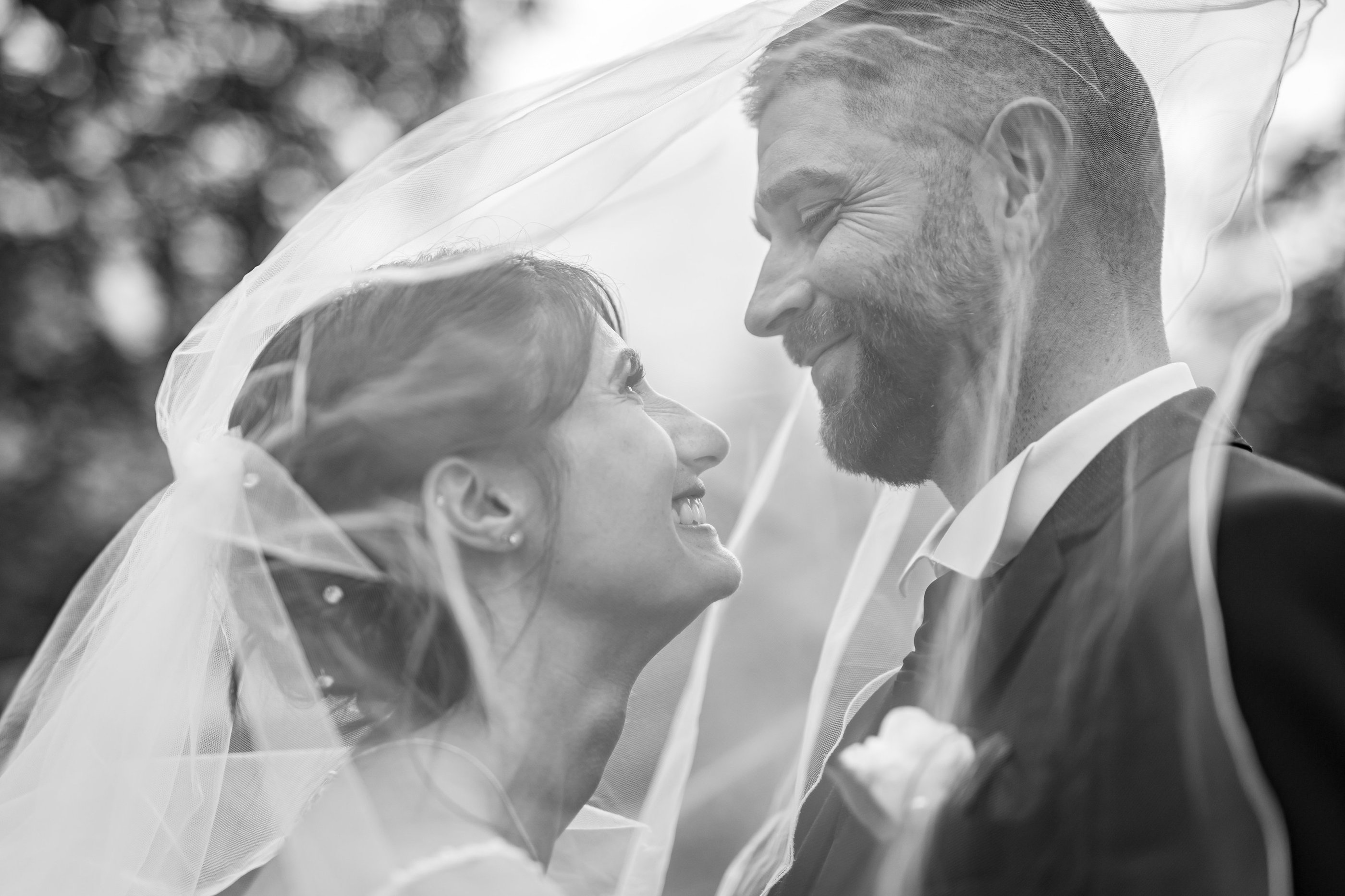 a bride and groom standing in front of a tree