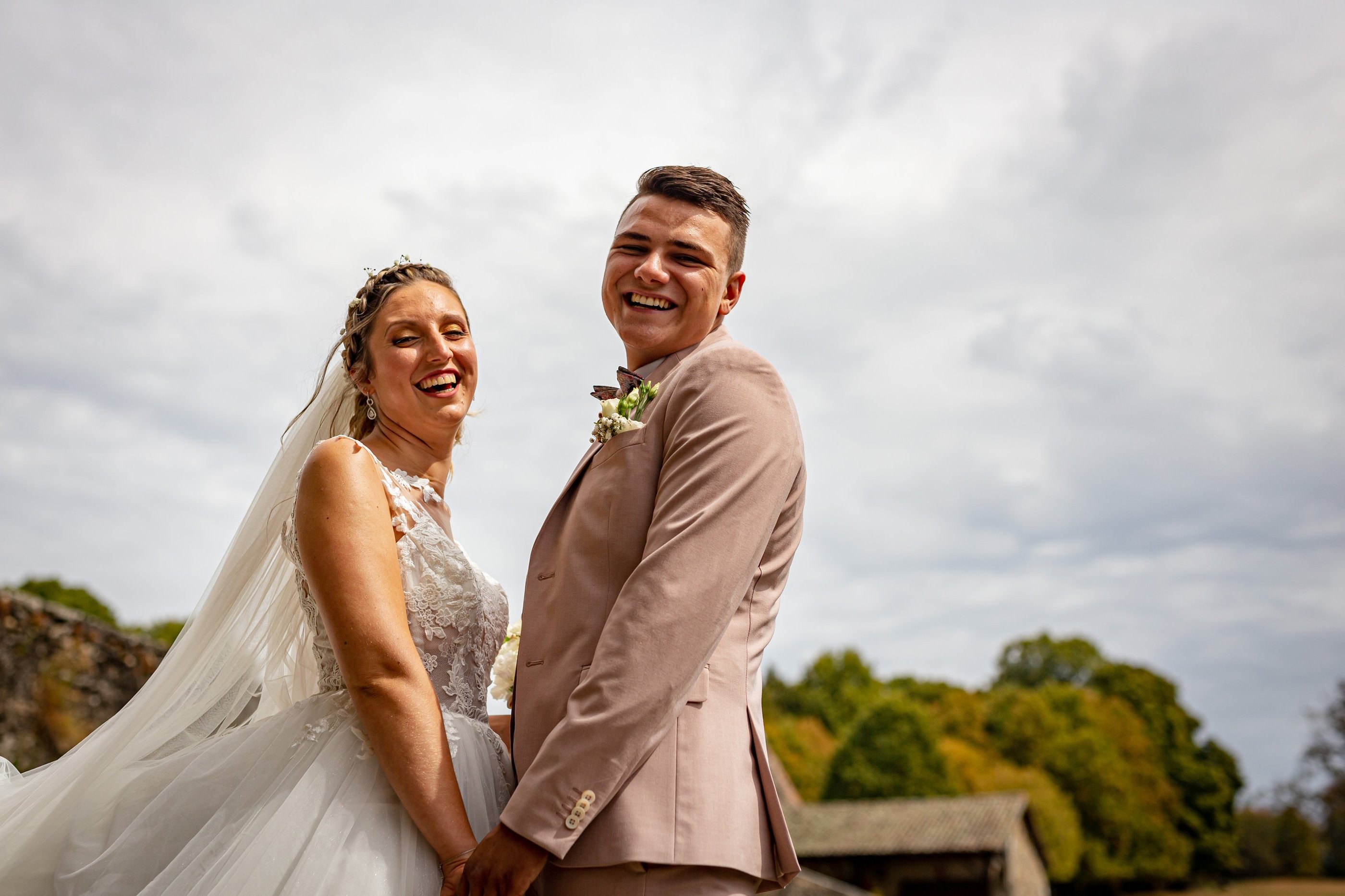 a bride and groom standing in front of a tree