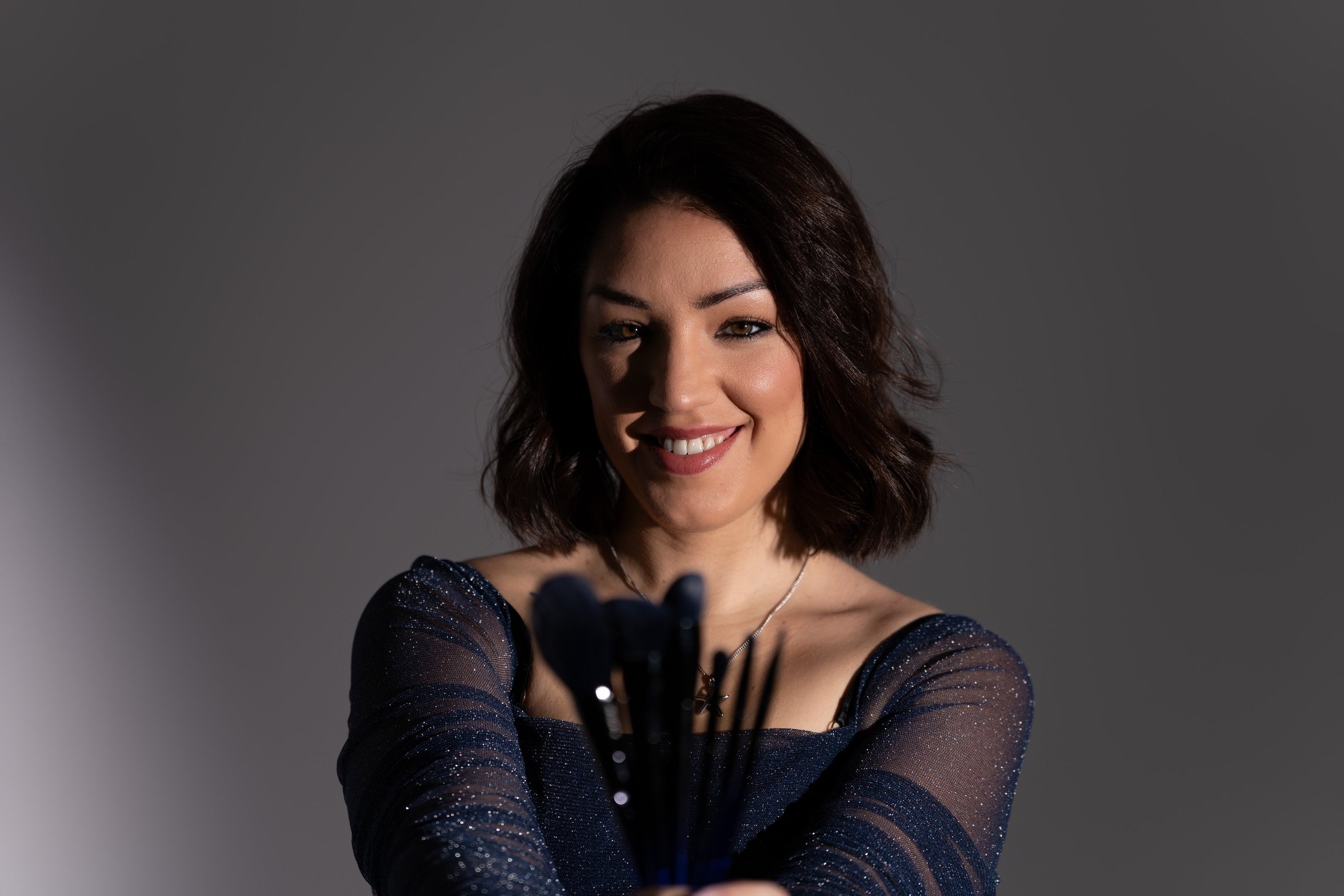 Professional makeup artist holding a set of brushes for a beauty studio portrait.