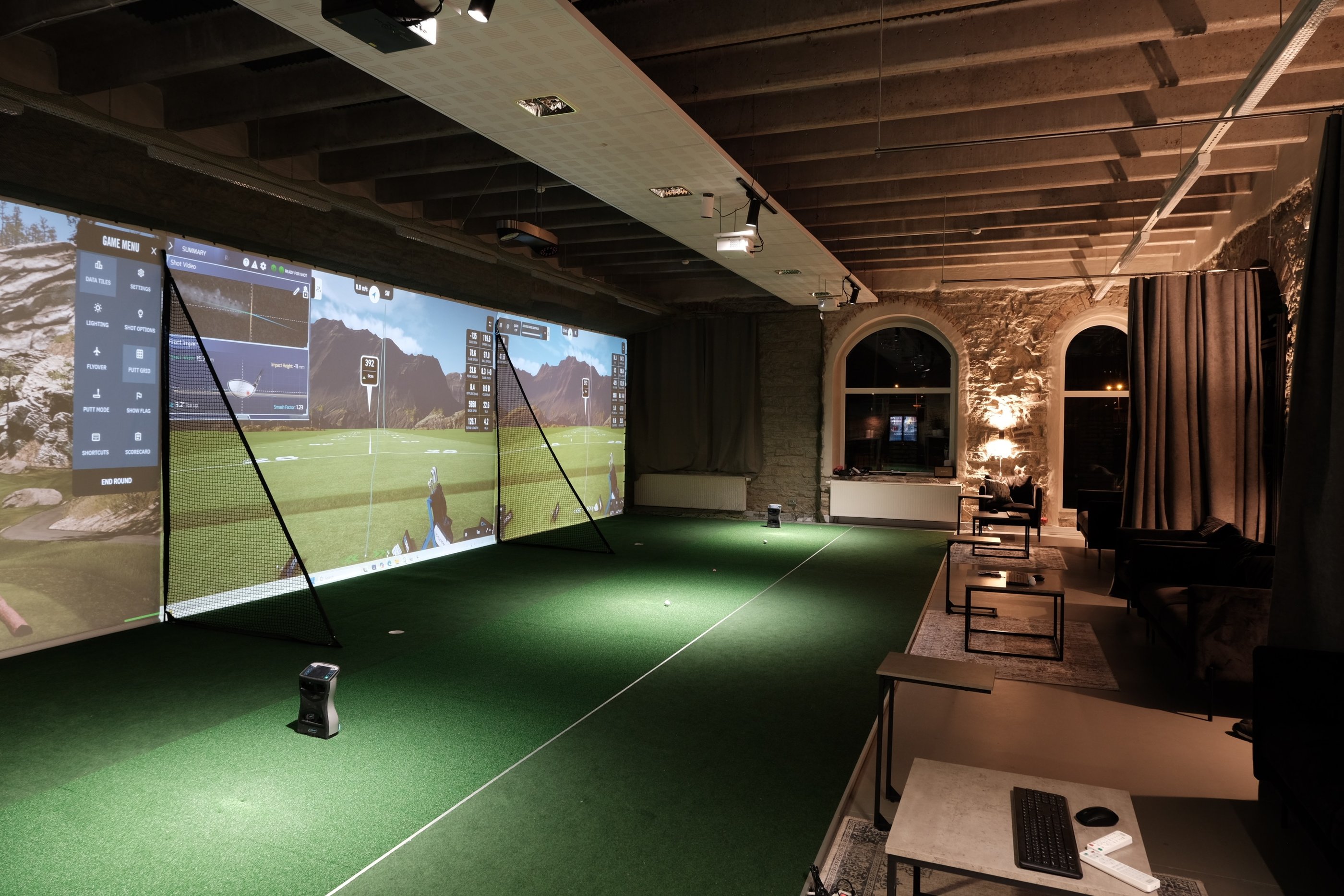 a man is playing golf in a room with a large screen