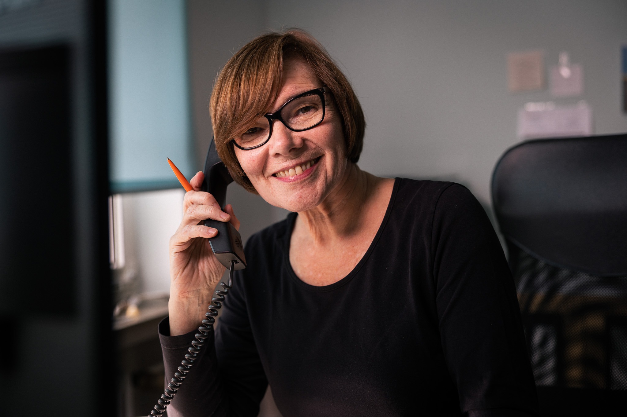 eine frau mit braunen haaren und brille spricht in ein telfon im atelier rohlfs