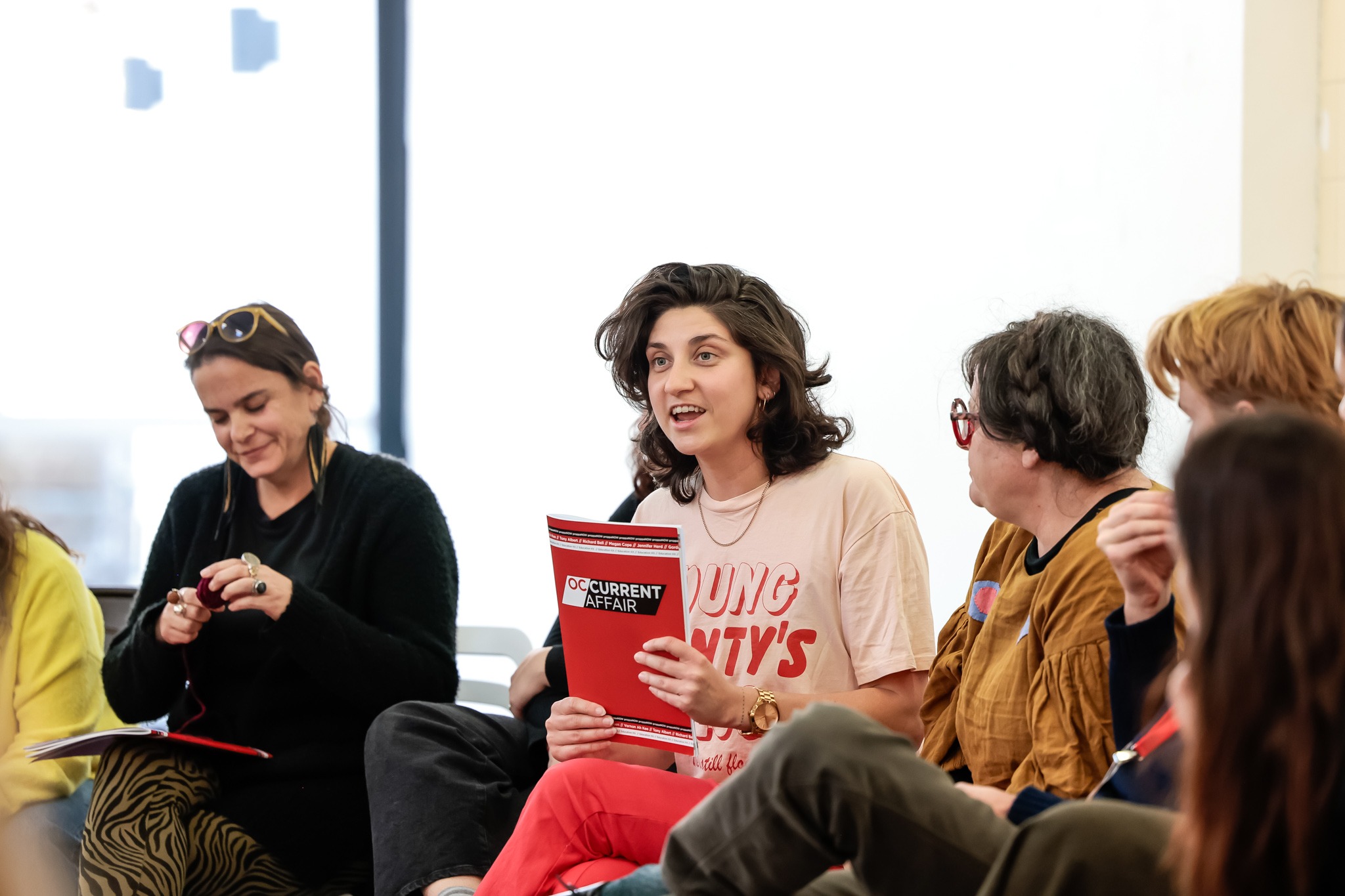 A person holding an education resource booklet up and smiling.