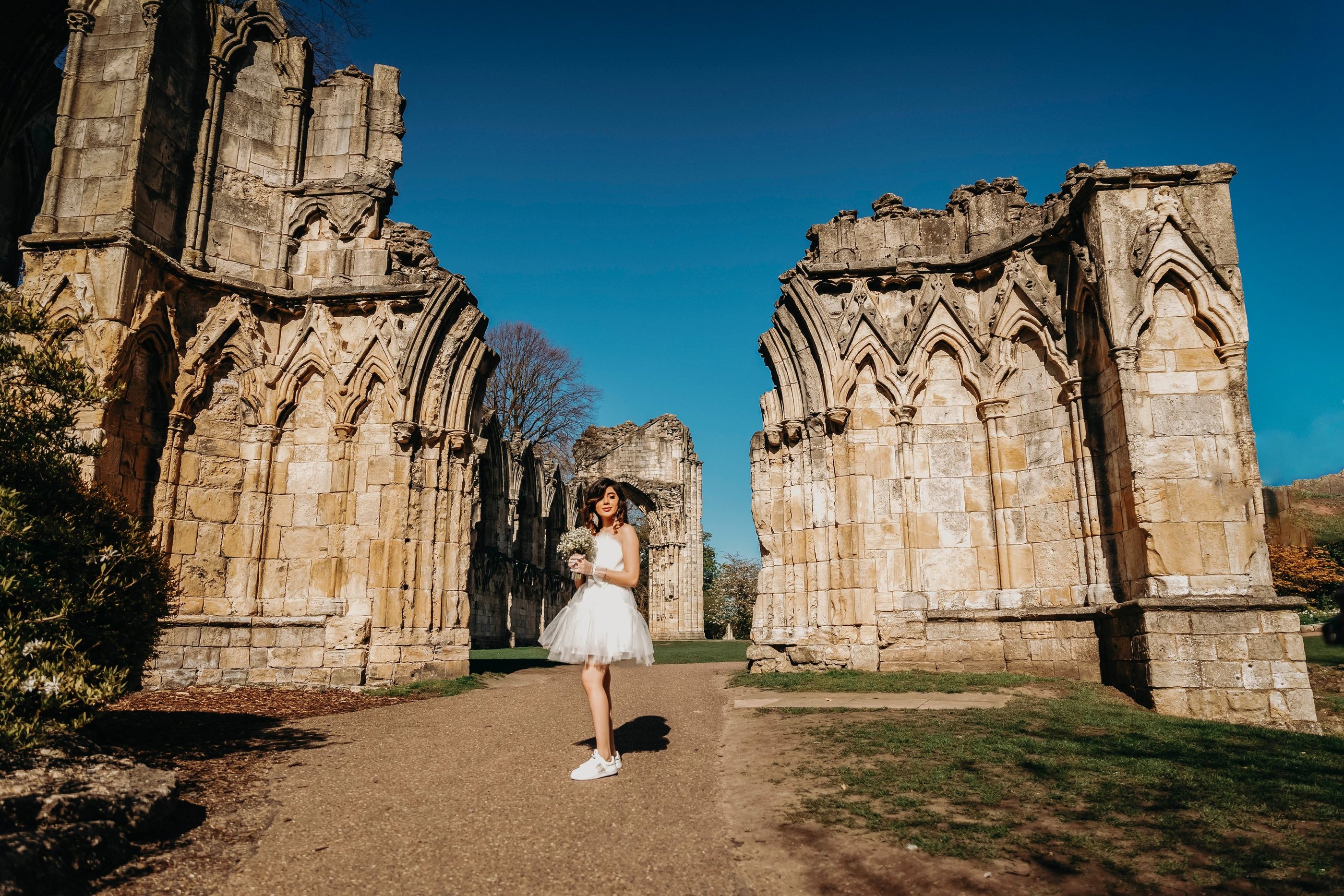 Bride walking between ancient stone arches in York, captured by Fred Art Studio.