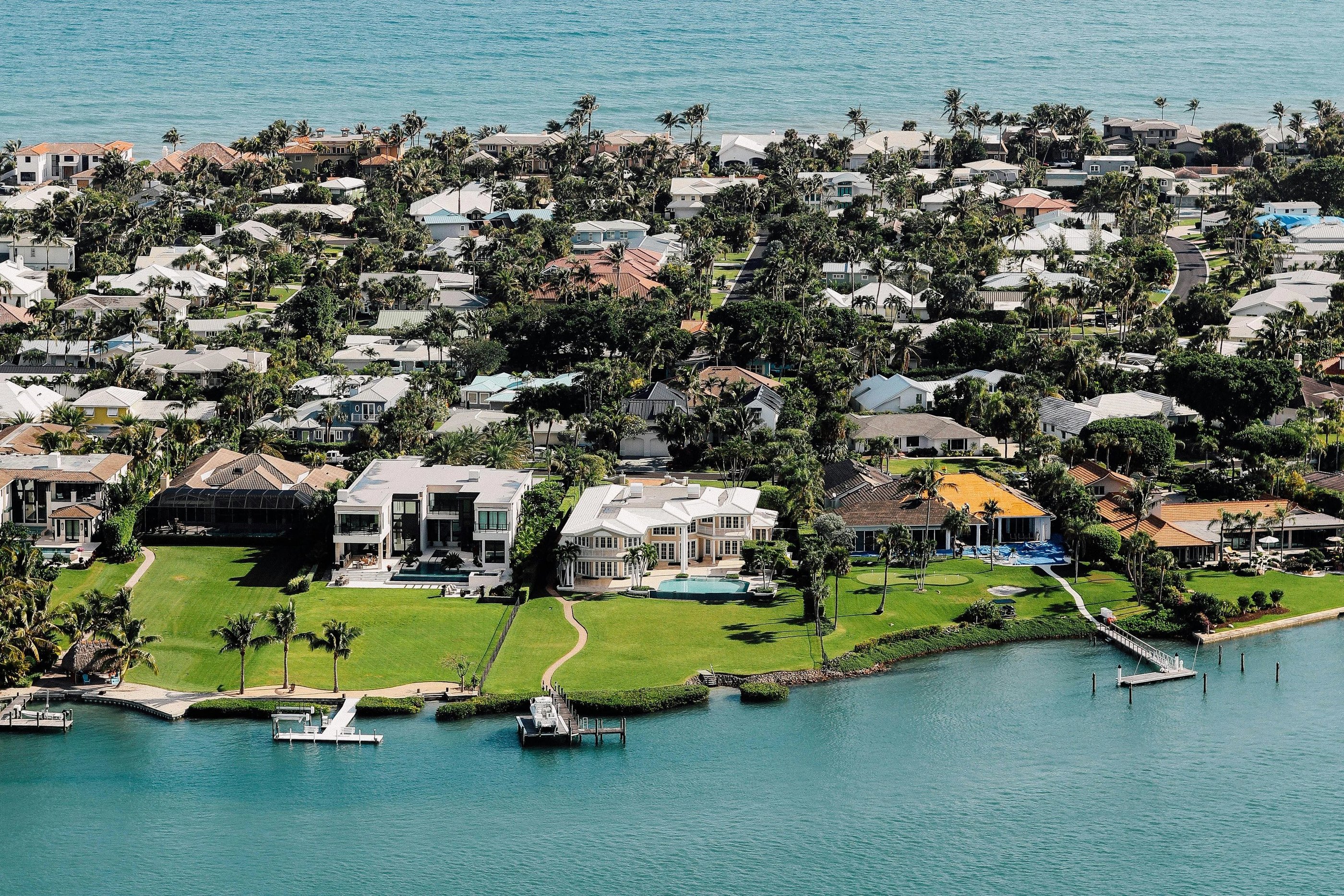 Aerial view of luxury waterfront real estate and coastal homes in a tropical Florida community.