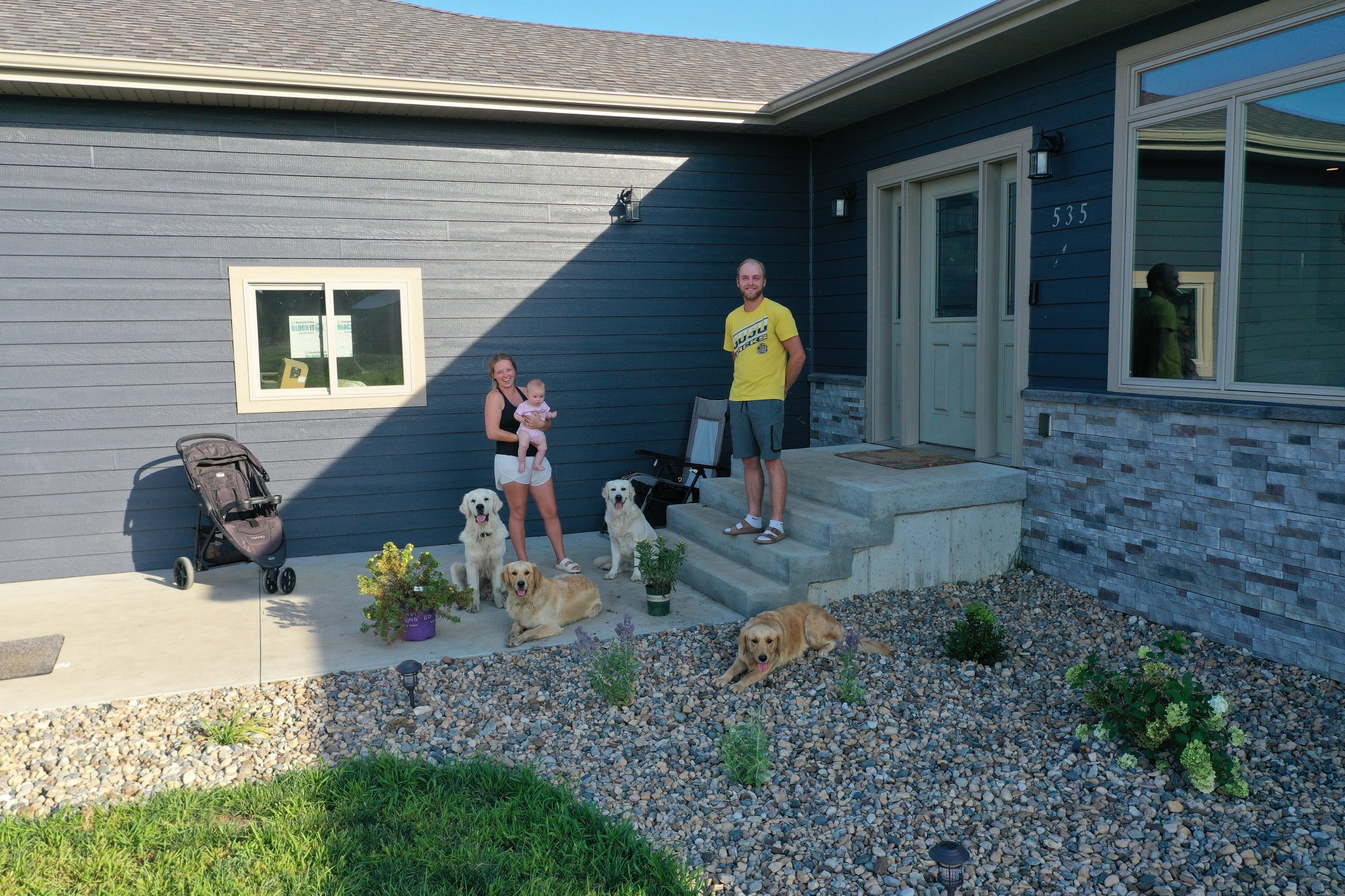 A family with their 4 dogs in front of a house