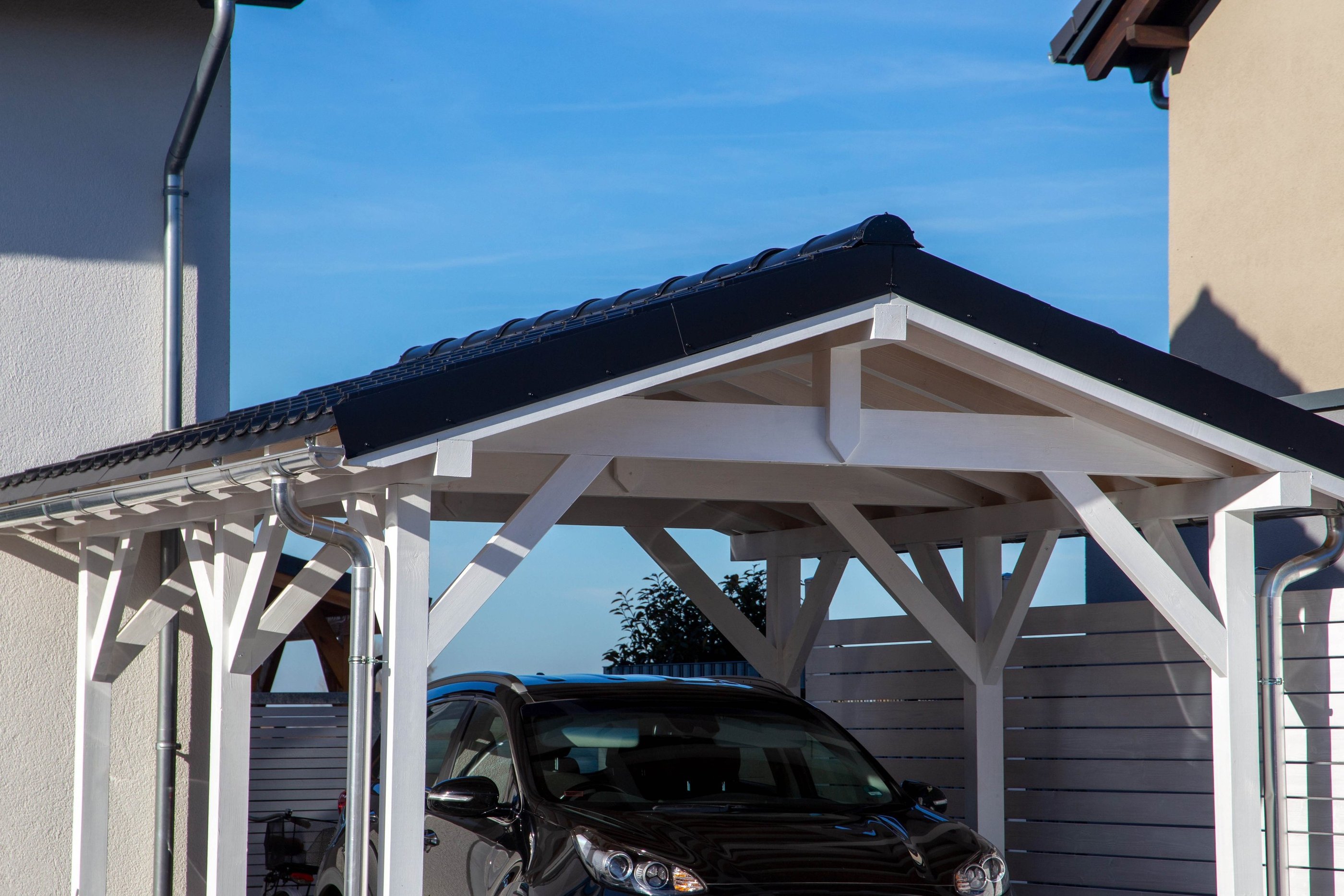carport en bois peint en blanc avec toiture tuile pour protéger une voiture