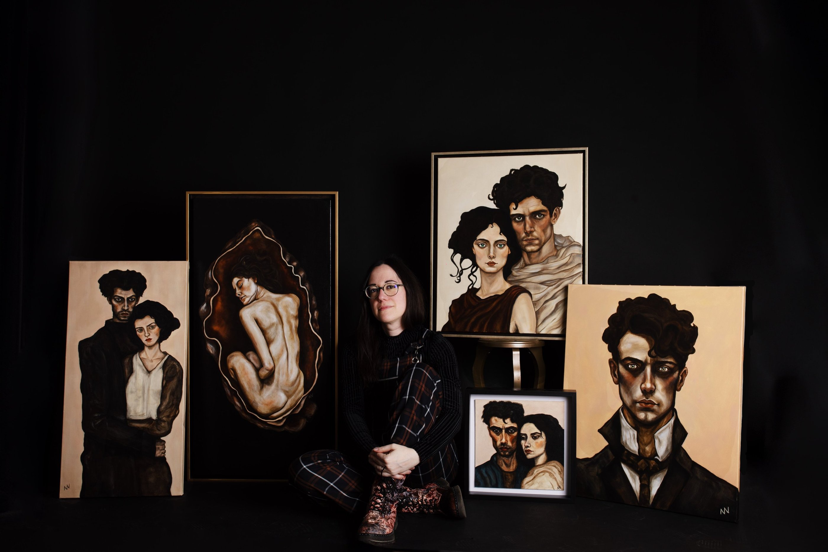 Artist manef photographed with a selection of original portrait paintings