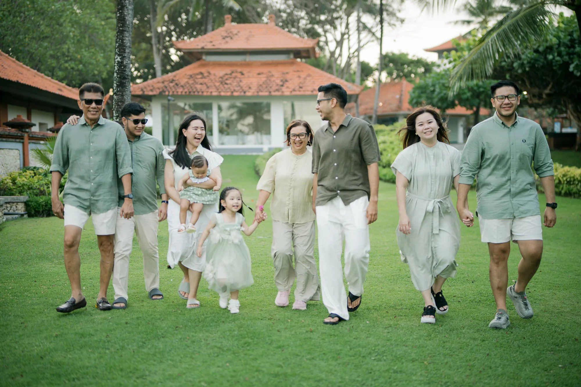 Multigenerational family walking together through a tropical garden during a Bali family photography session.