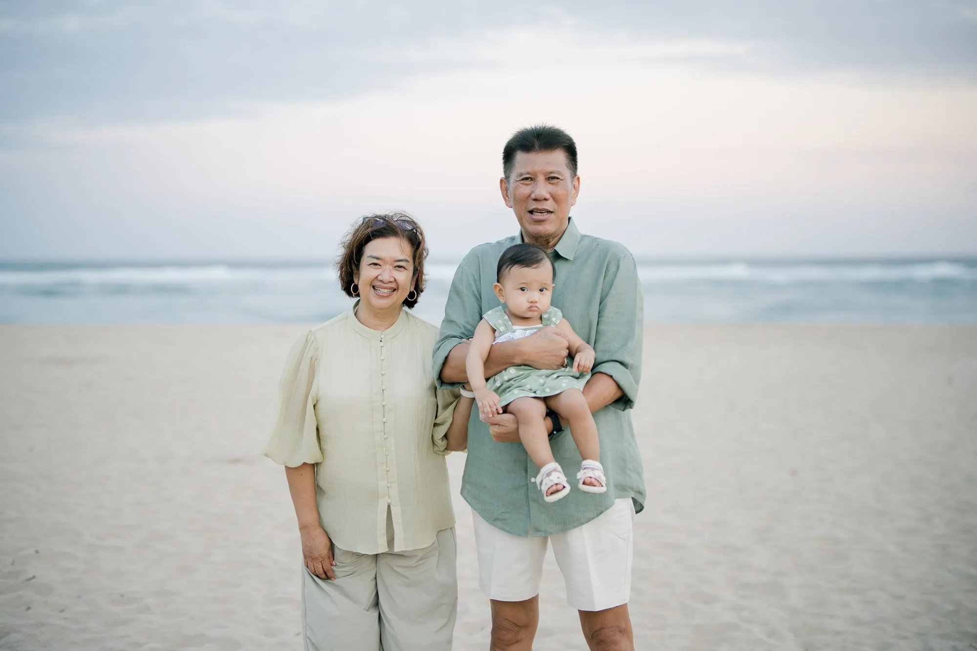 Grandmother standing with her grandchild during a multigenerational family photography session on a Bali beach.
