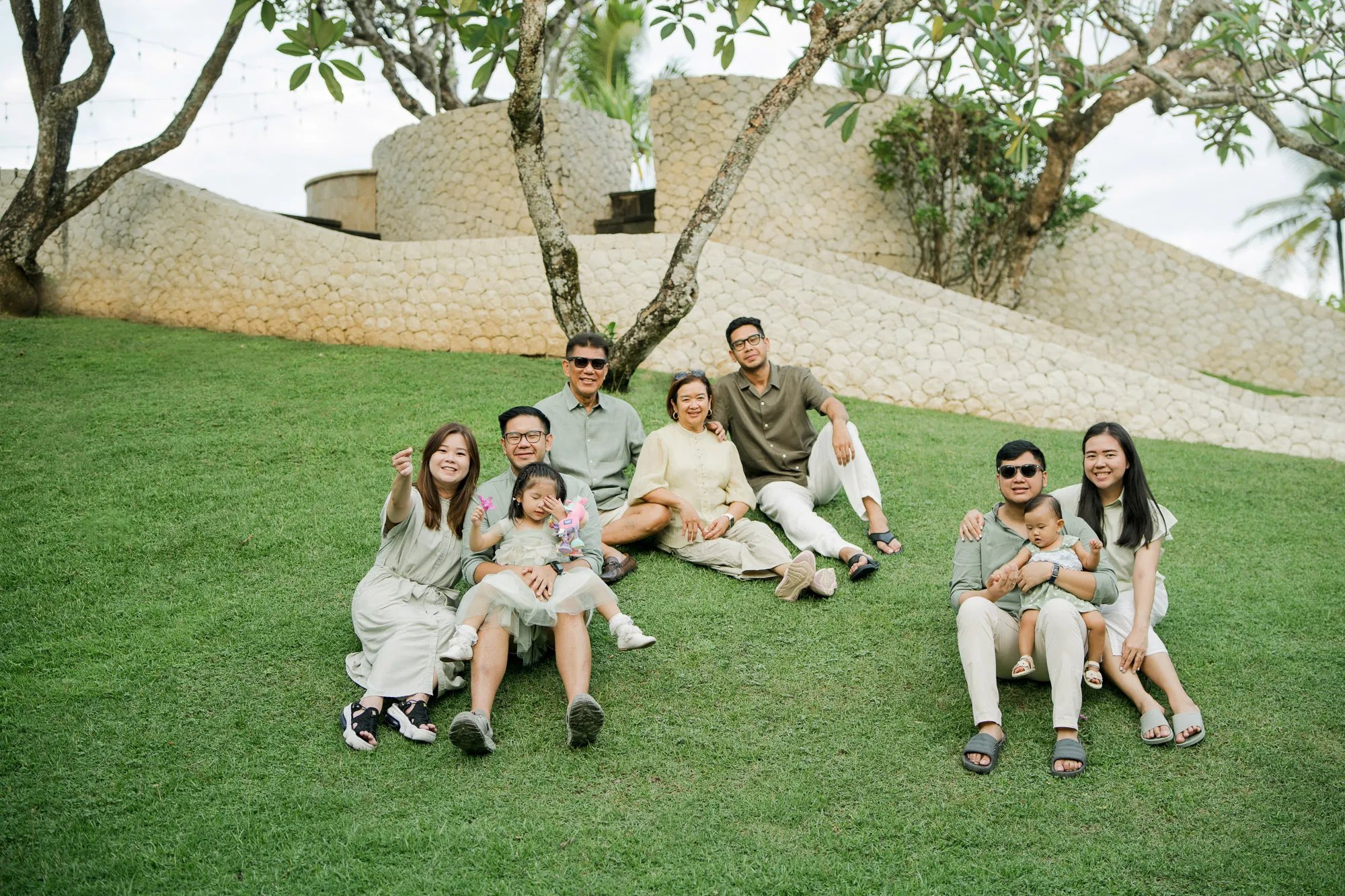 Extended family gathered together on a resort garden lawn during a multigenerational family photography session in Bali.
