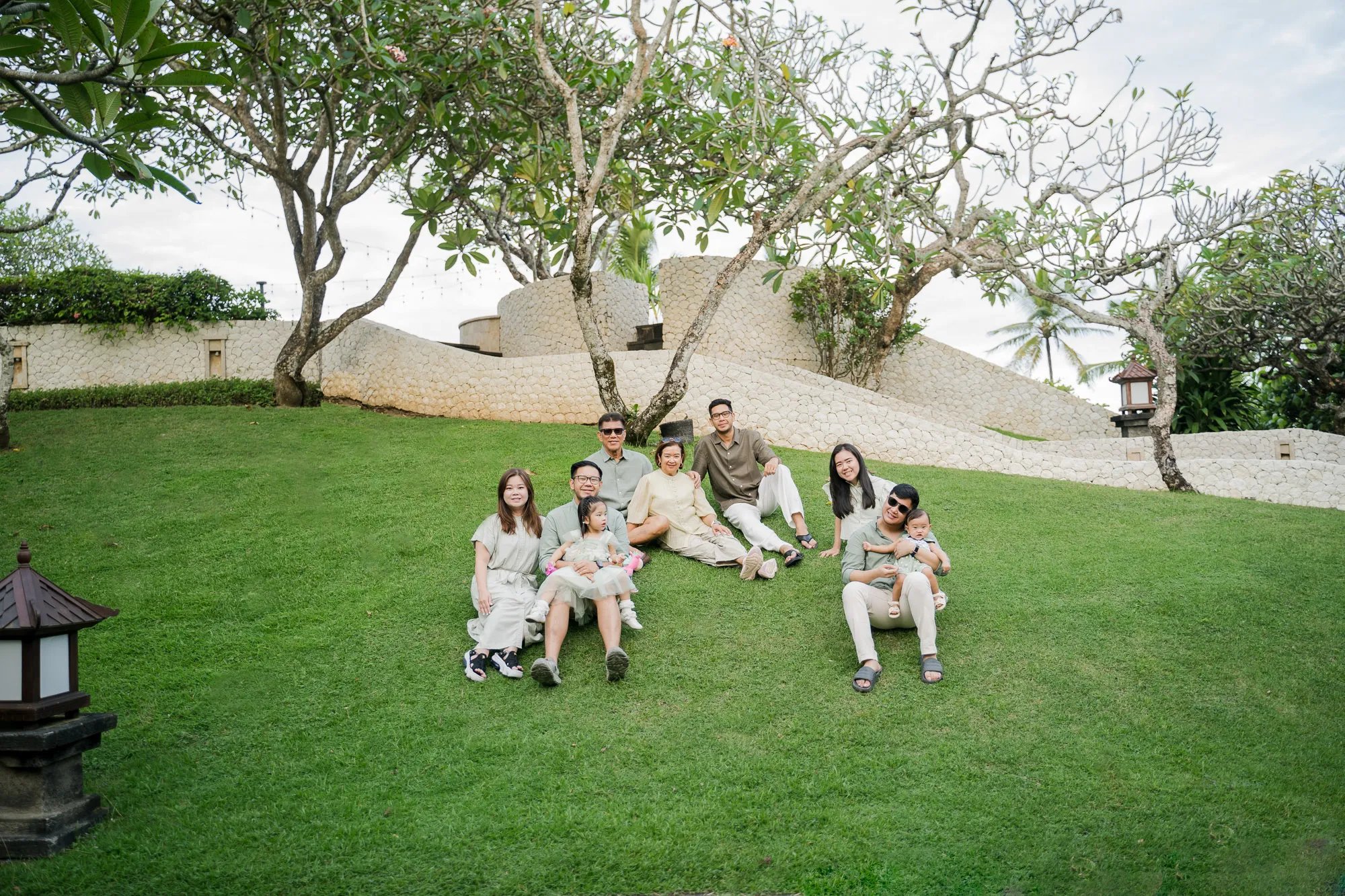 Three generation family gathered on a tropical garden lawn during a family photography session in Bali.