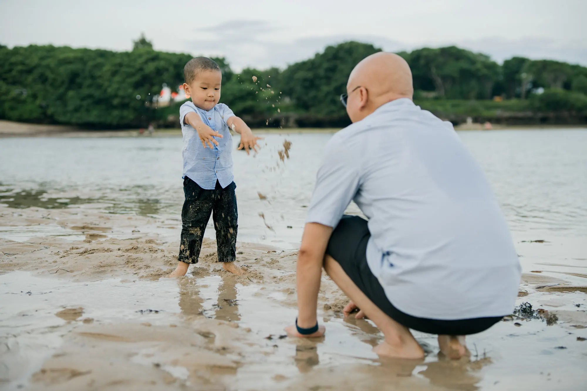 Father playing with his son by the shoreline during a family photography session at Nusa Dua Beach