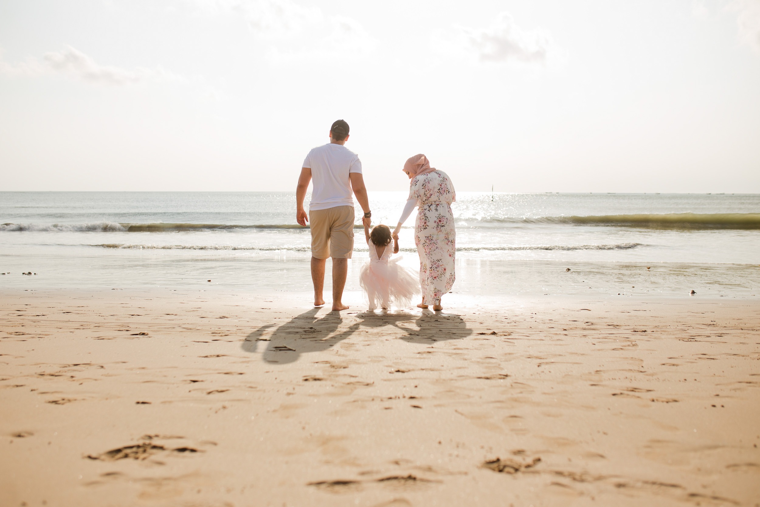 family session Jimbaran Beach Bali parents walking with child at sunset beach