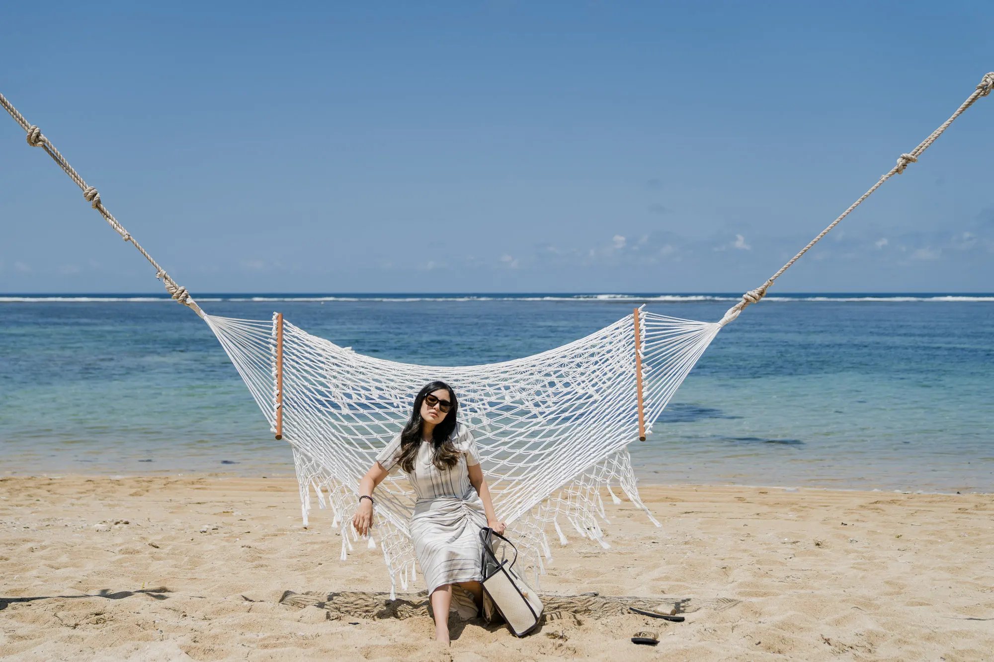Woman sitting on a beach hammock at Samabe Bali Suites & Villas in Nusa Dua.