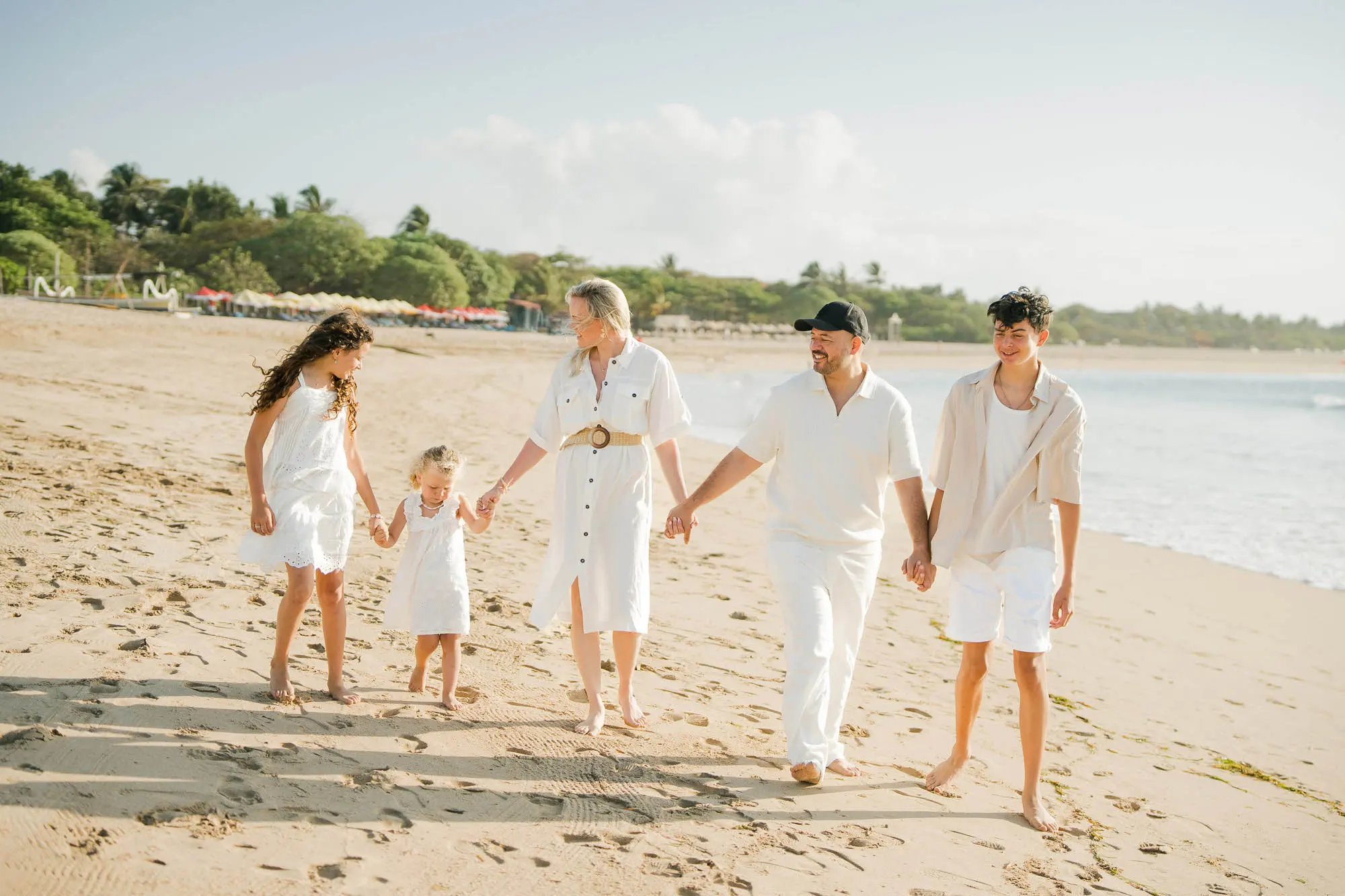 Family walking together along the shoreline during a family photography session at Ayodya Resort Bali