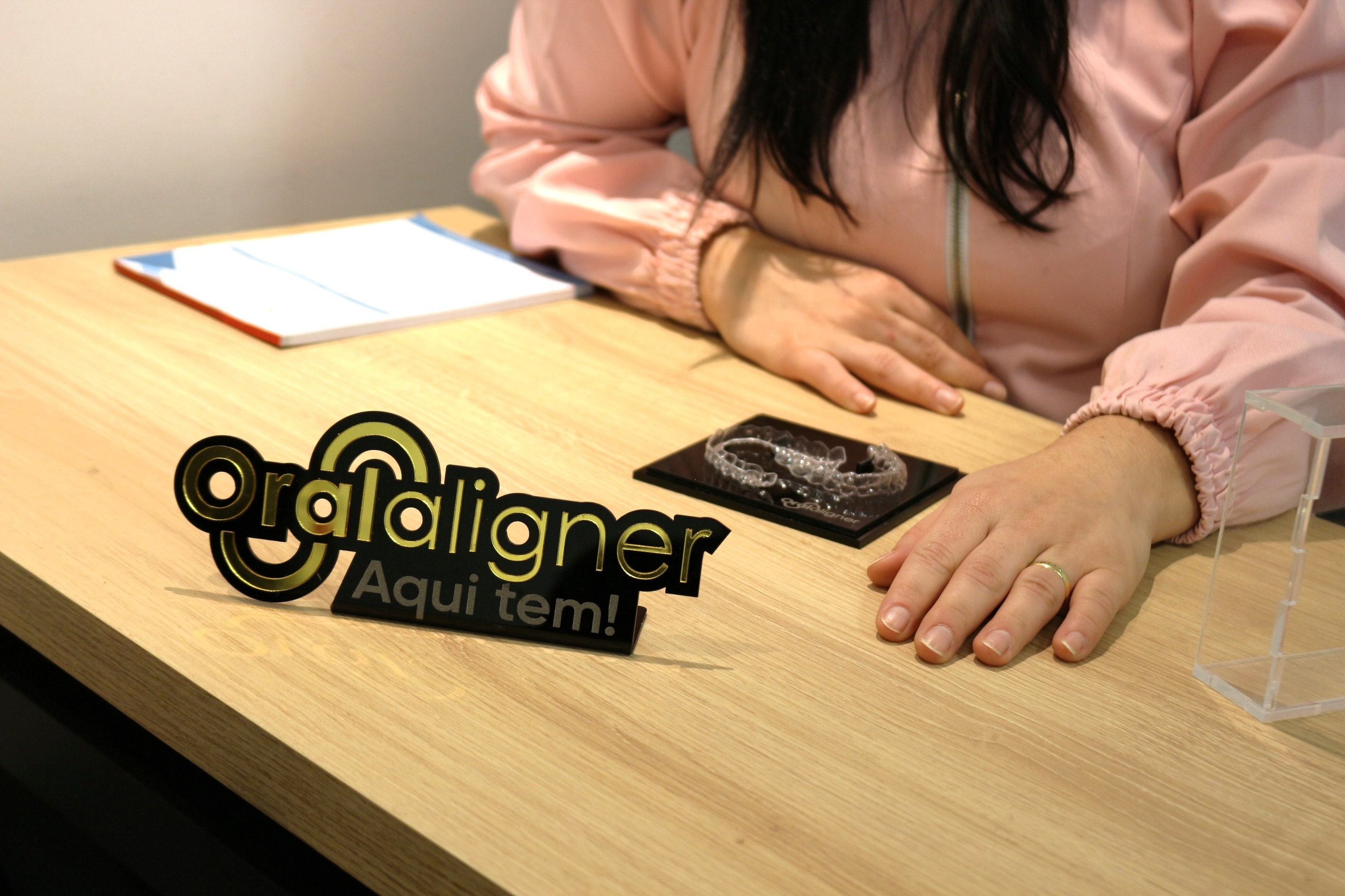 a woman sitting at a table with a invisible teeth aligner in front of her