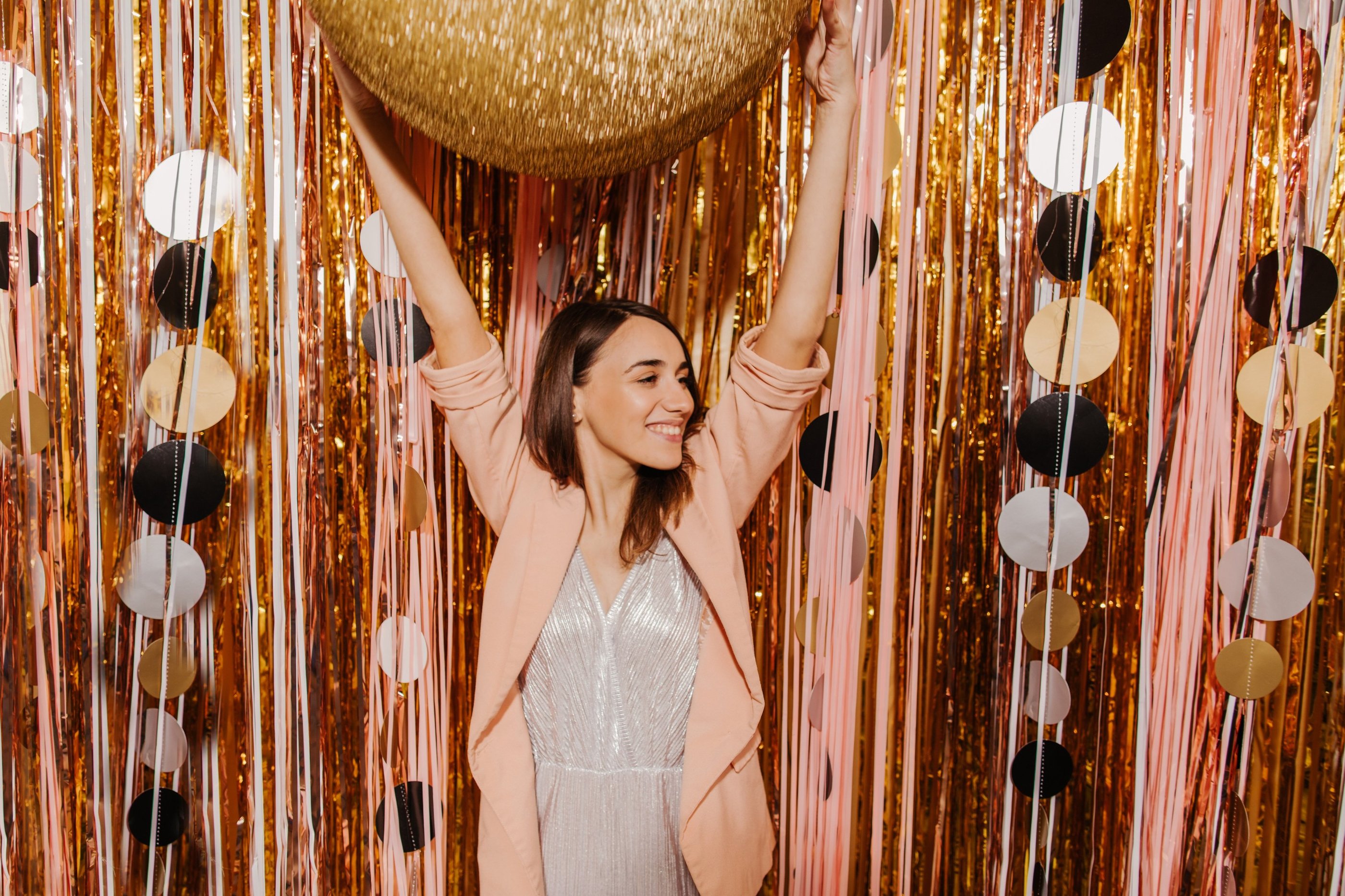 une femme vêtue d'une robe argentée et d'un ballon doré Se fait prendre en photo par un Photo Booth 