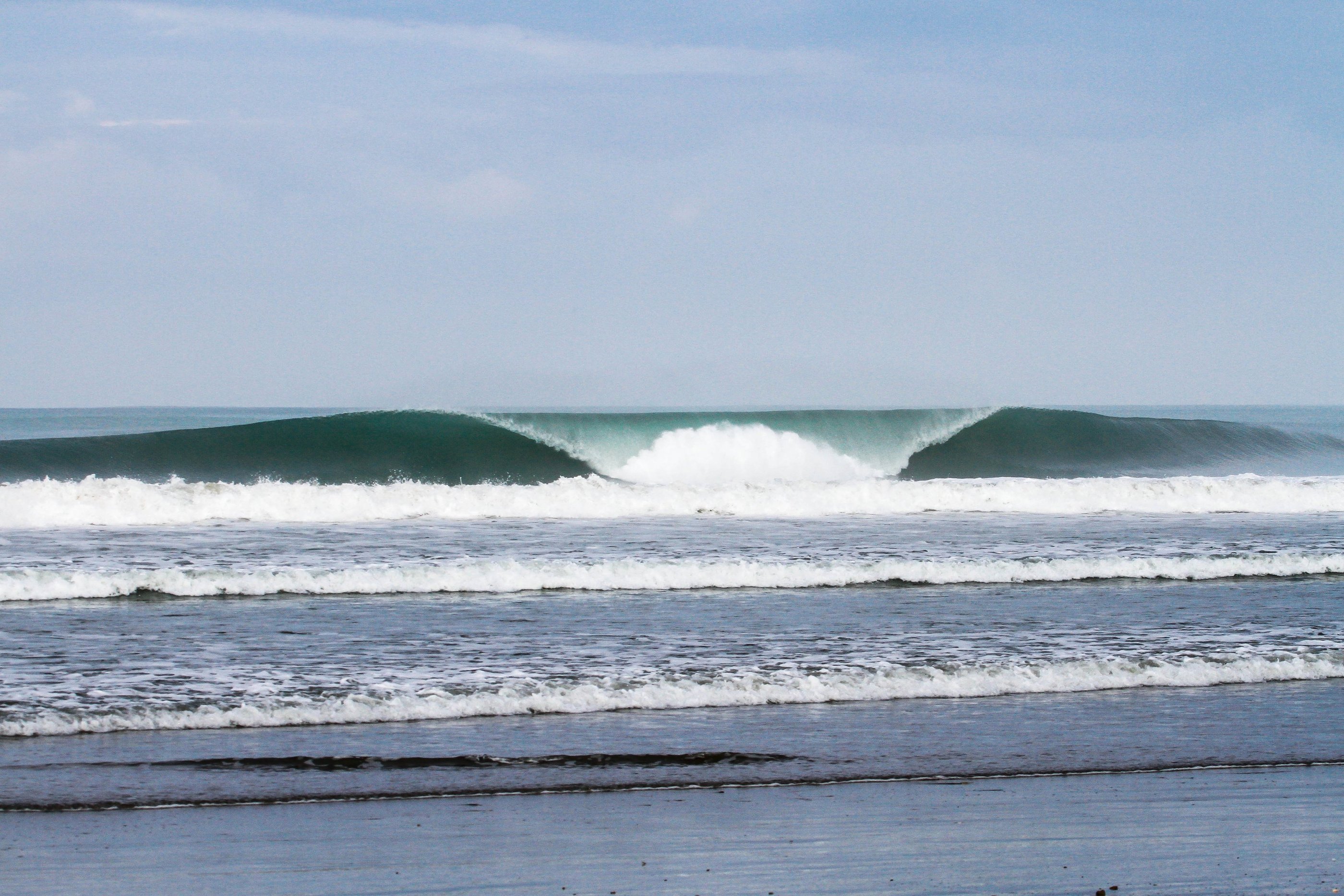 A clean wave rolling and breaking to shore left and right