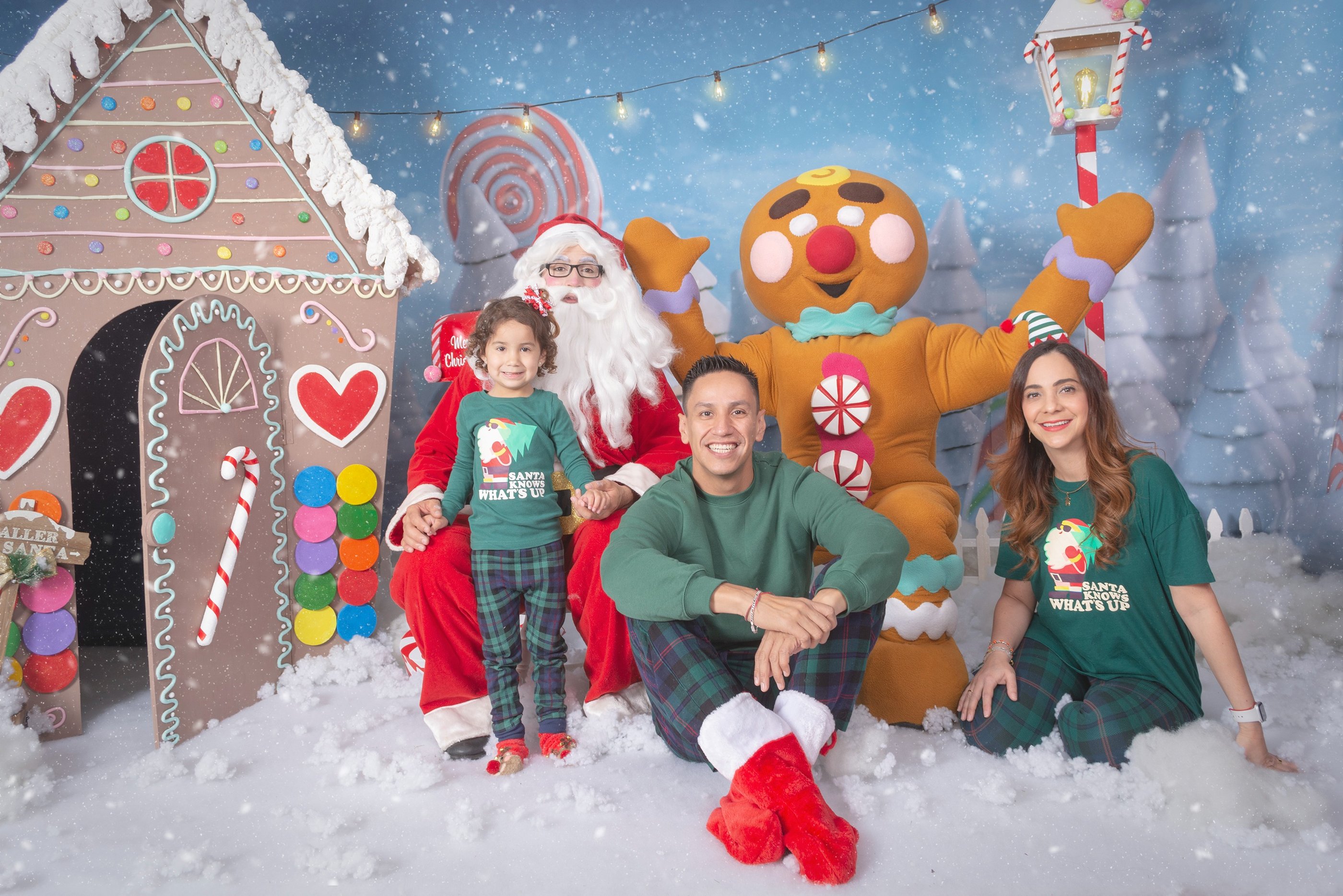 a family posing for a photo in front of a gingerbread house