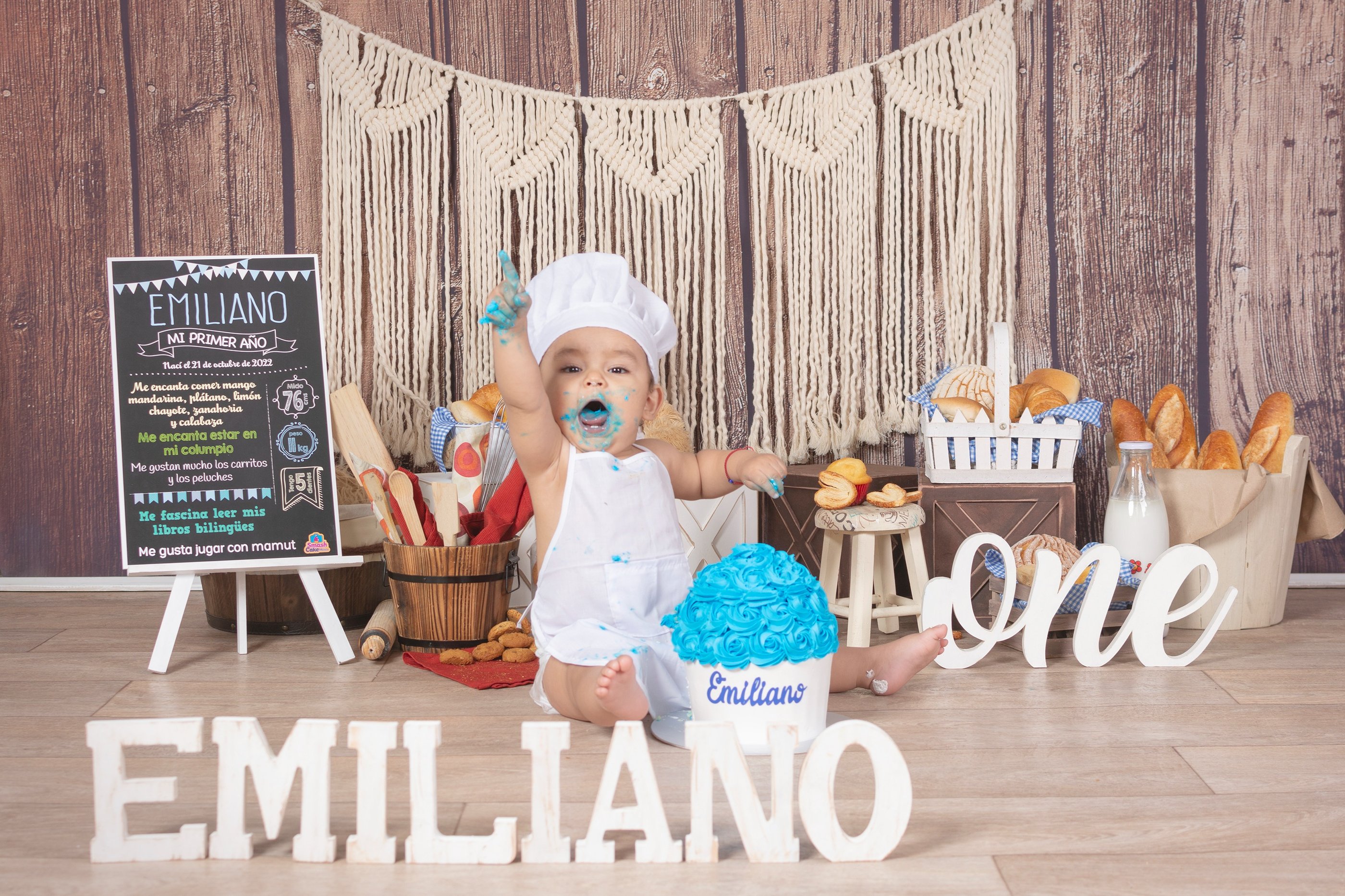 a baby boy in a white dress and a cake