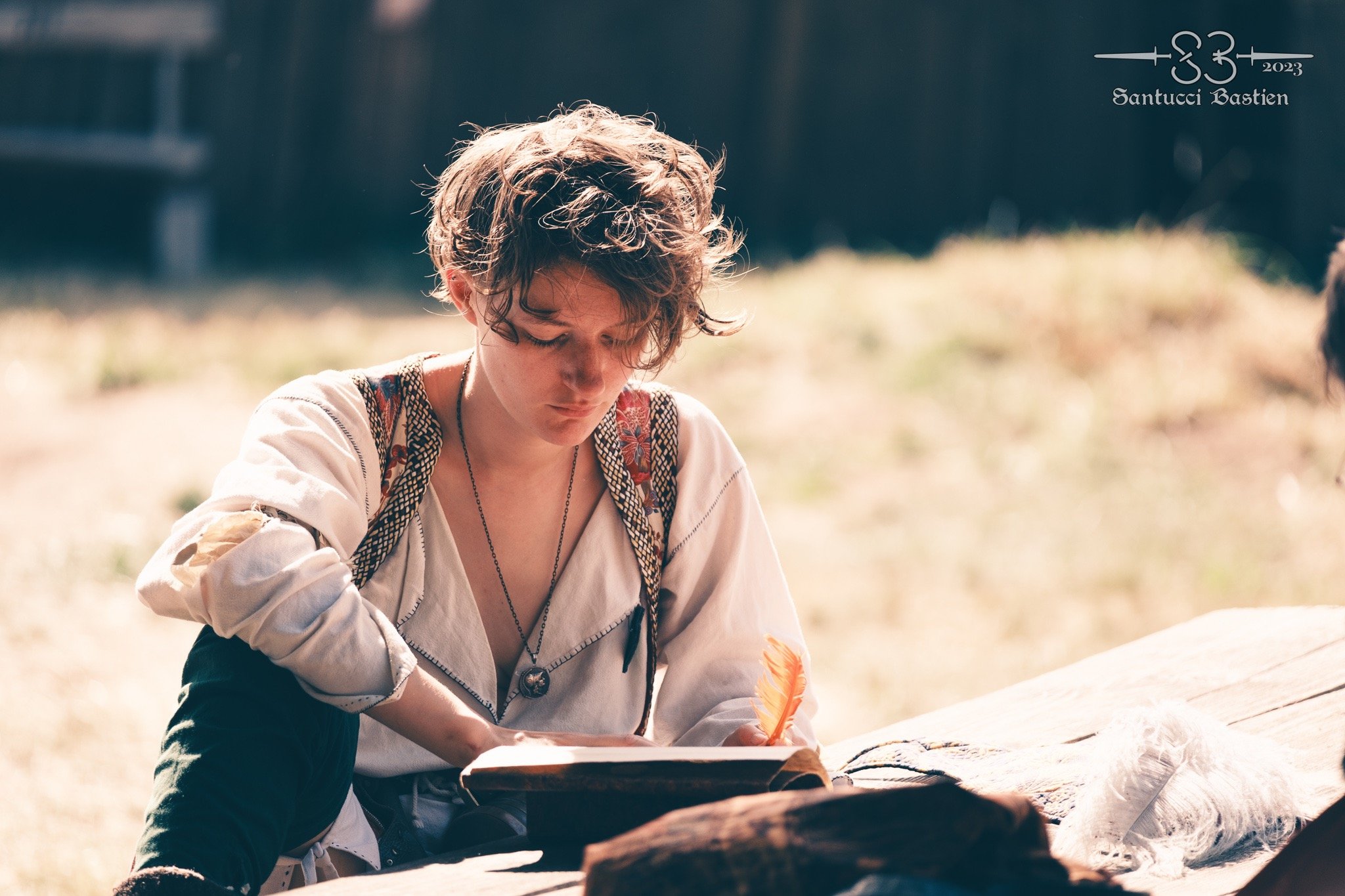 Plan d'une personne en tenue médiévale écrivant dans un livre avec une plume