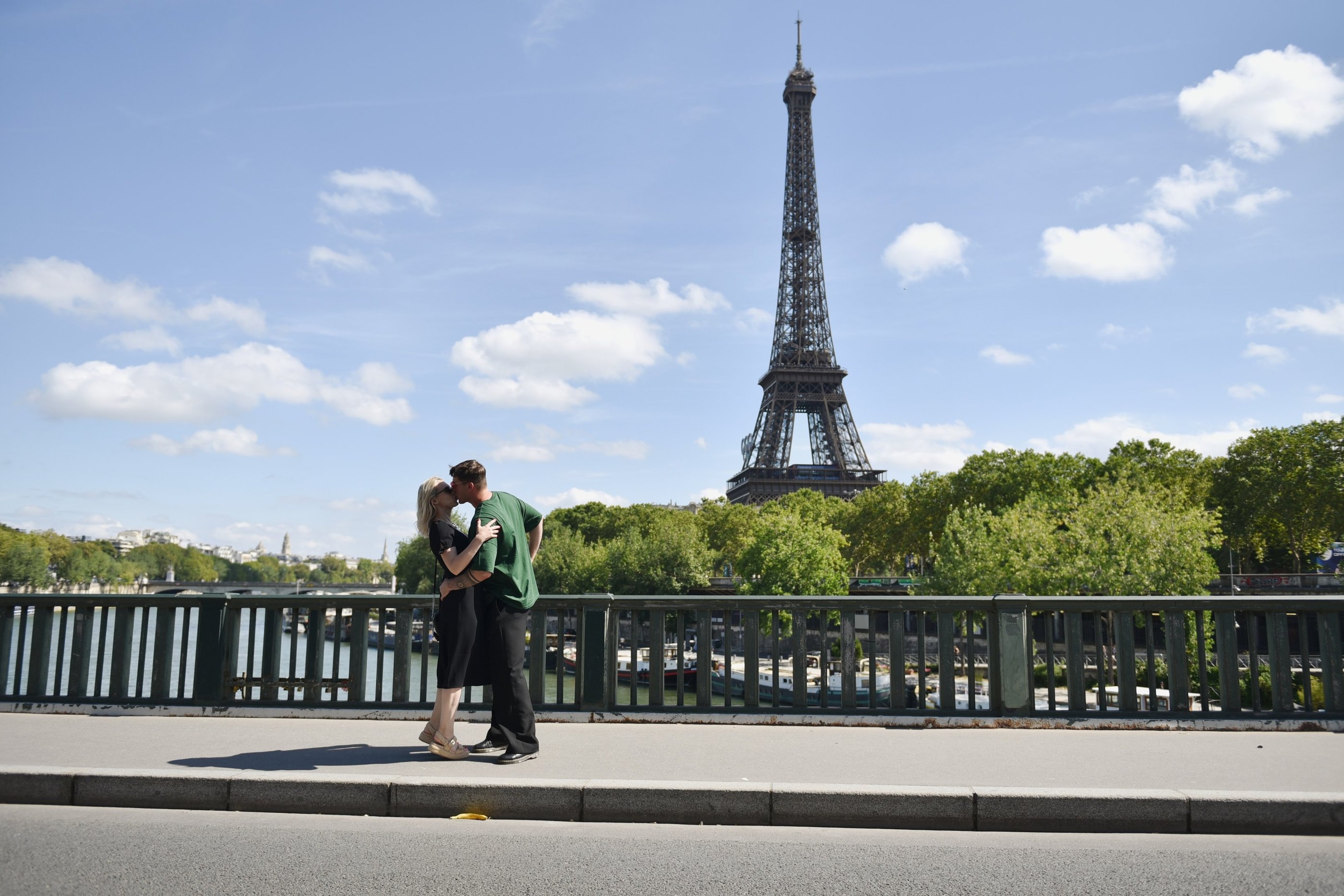 Deux amoureux s'embrassent sur le pont bir hakeim avec la tour eiffel en fond, il fait beau