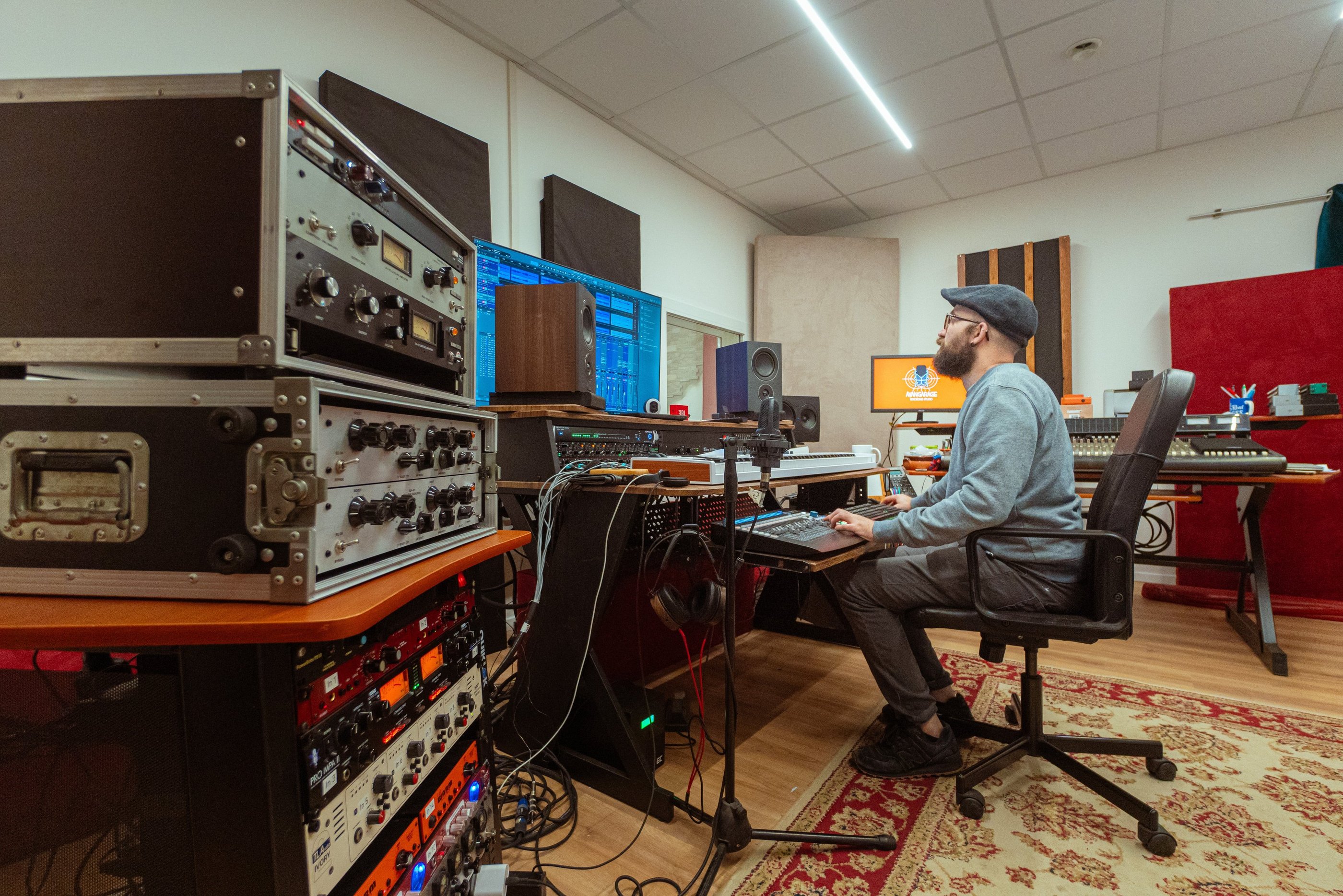 A sound engineer works in a professional music studio with analog gear, mixing consoles, and monitors.