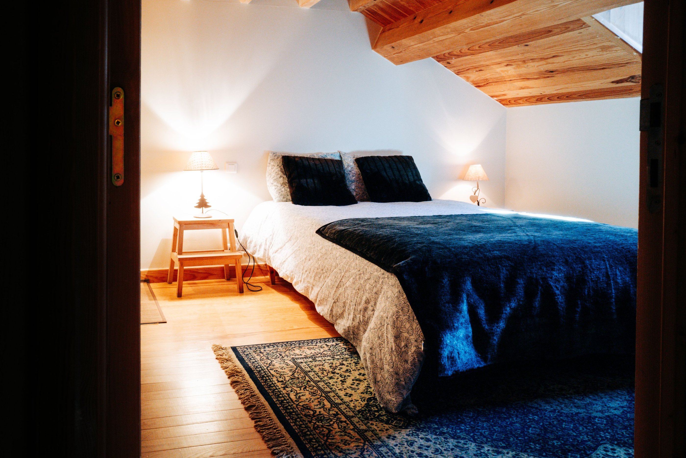 lit entouré de chevets avec coussins, plaid et tapis 