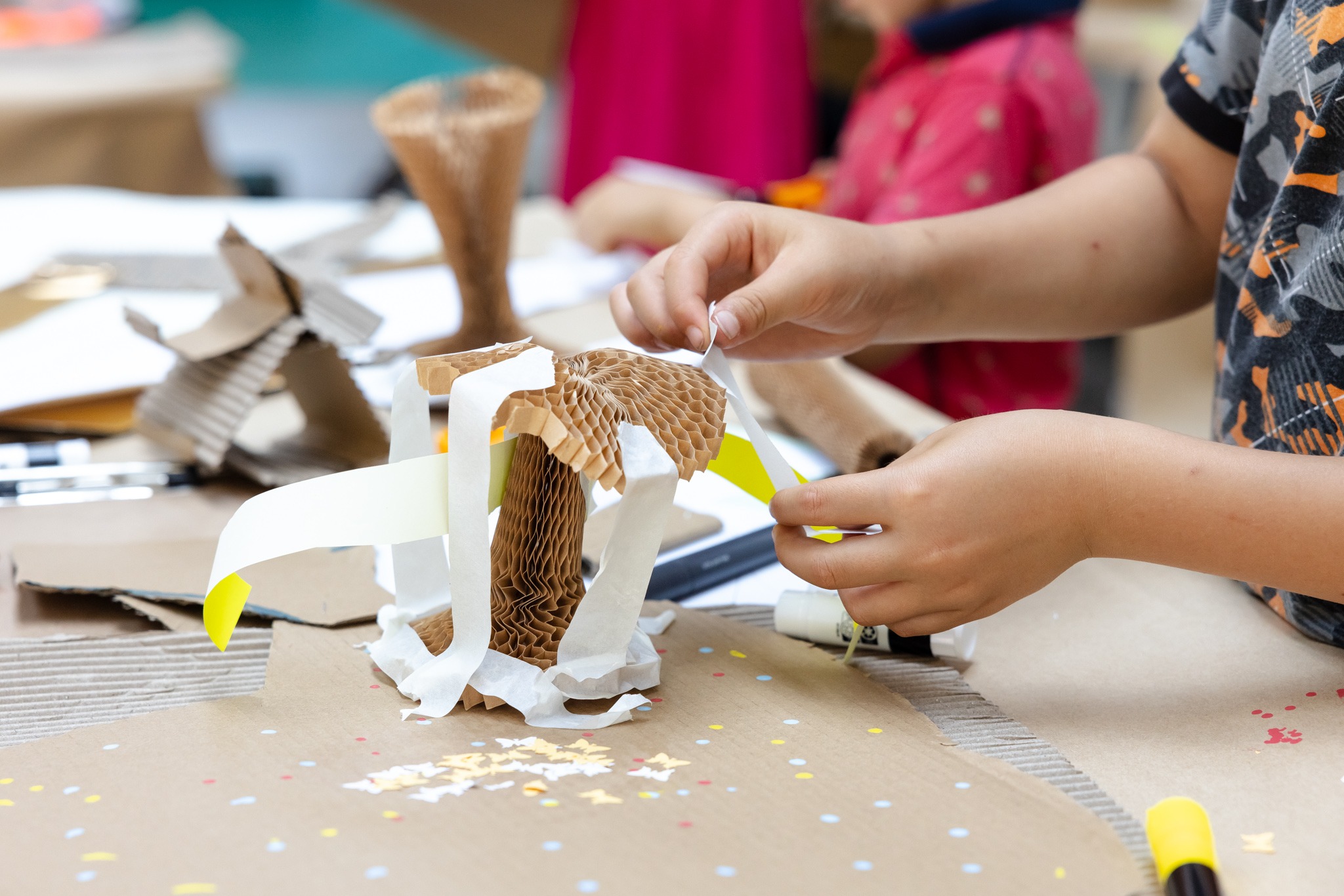 A child sticking paper strips to a concertina cardboard structure.
