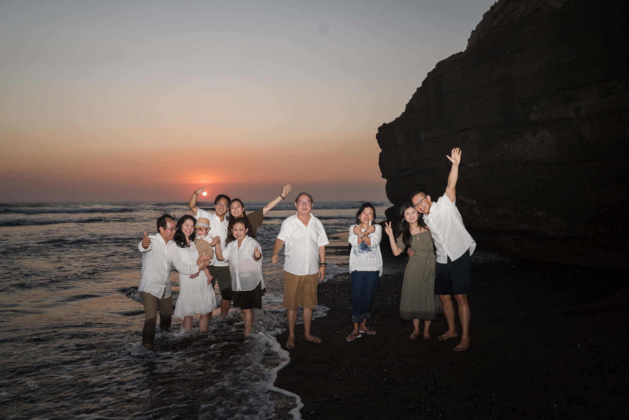 Extended family enjoying a sunset moment together at Nyanyi Beach Tabanan Bali during a relaxed family photography session