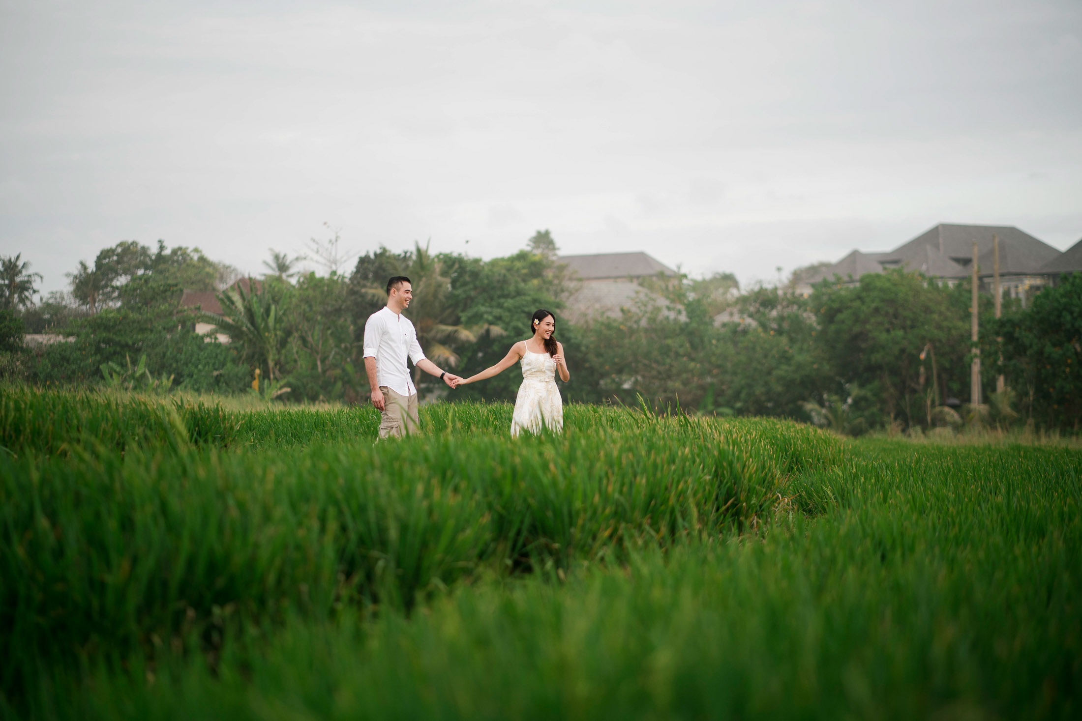 Couple walking through green rice fields at Waka Gangga resort in Tabanan West Bali