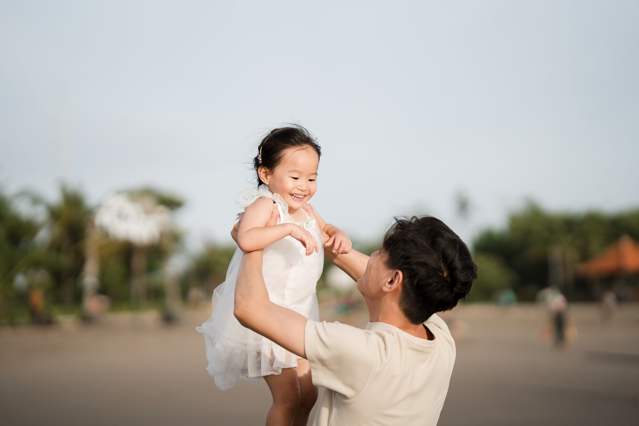 Father lifting his daughter during a joyful family photography session at Petitenget Beach Seminyak Bali